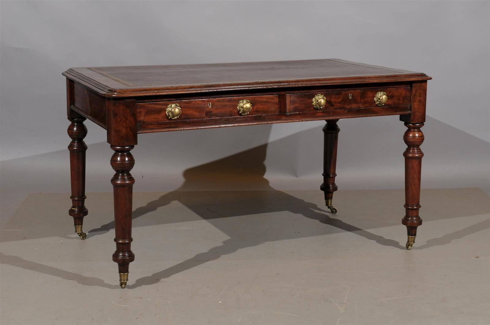 19th century English writing table with brown leather top, two drawers and turned legs.