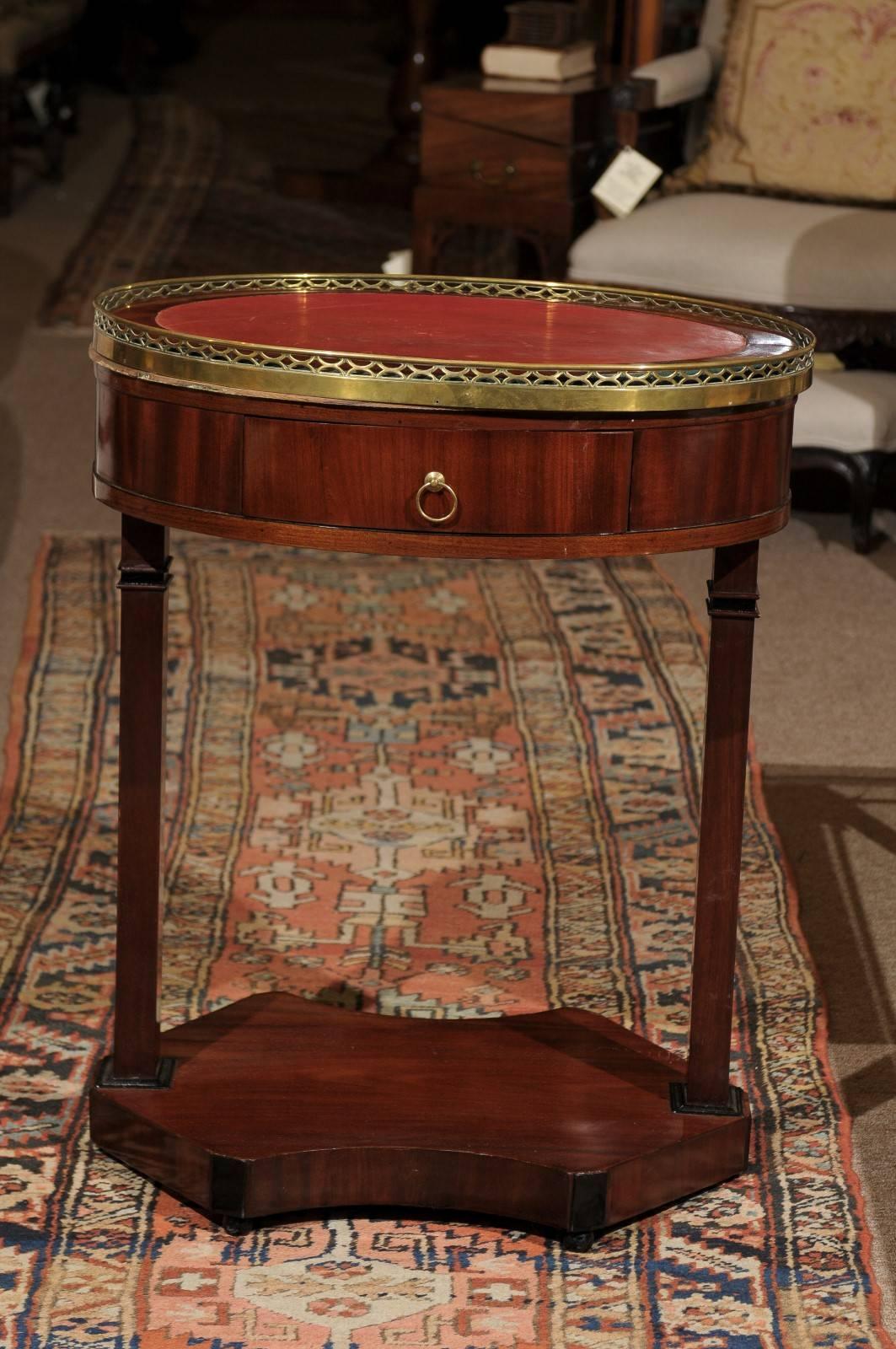 19th century French Empire mahogany oval table with marble top, brass gallery and red leather inset.