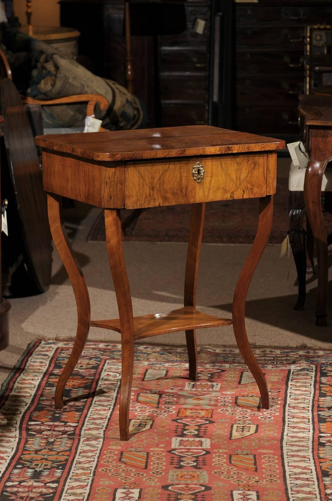 Early 19th century Italian walnut table with saber leg and lower shelf.

