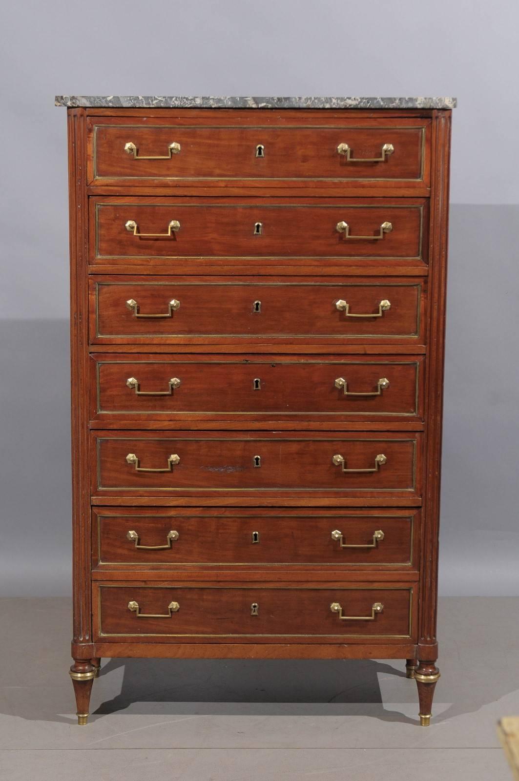 18th century French Louis XVI period six-drawer semanier in mahogany with grey marble top and turned legs. There are five (5) standard drawers and one (1) deeper or double drawer on the bottom. Brass inlay in drawers and brass mounts on feet.