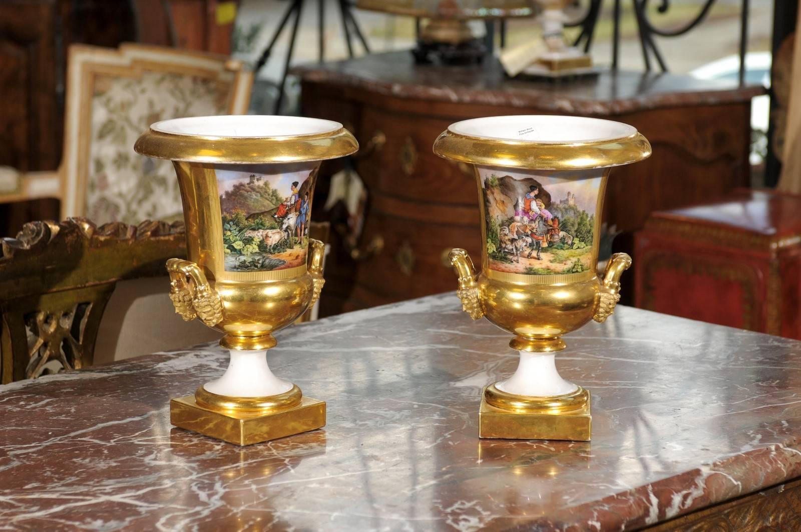 Pair of 19th century French Paris porcelain urns with painted scenes and handles.