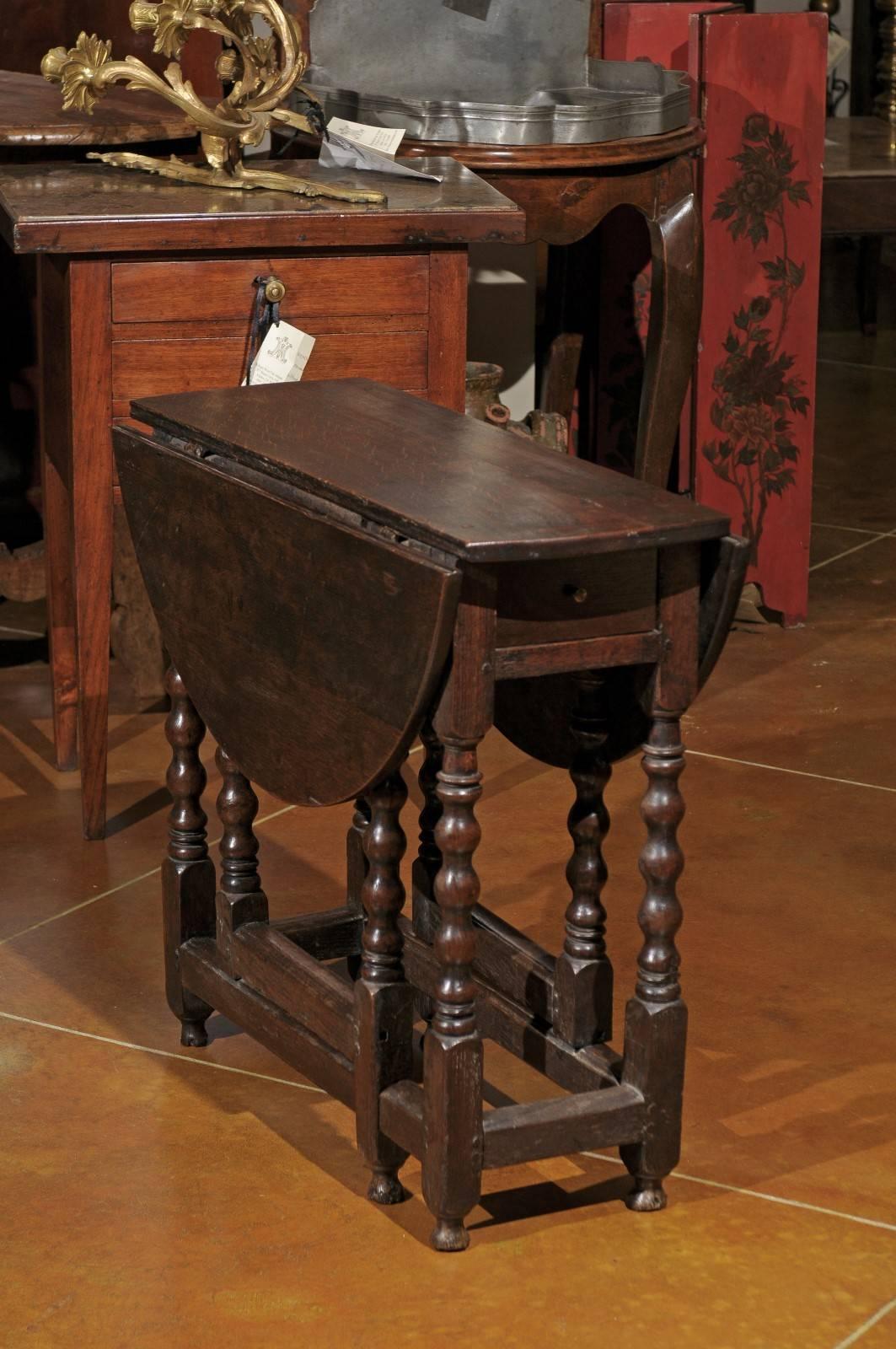 A 19th century English oak gate leg drop-leaf table with bobbin turned legs, stretcher and round feet.
