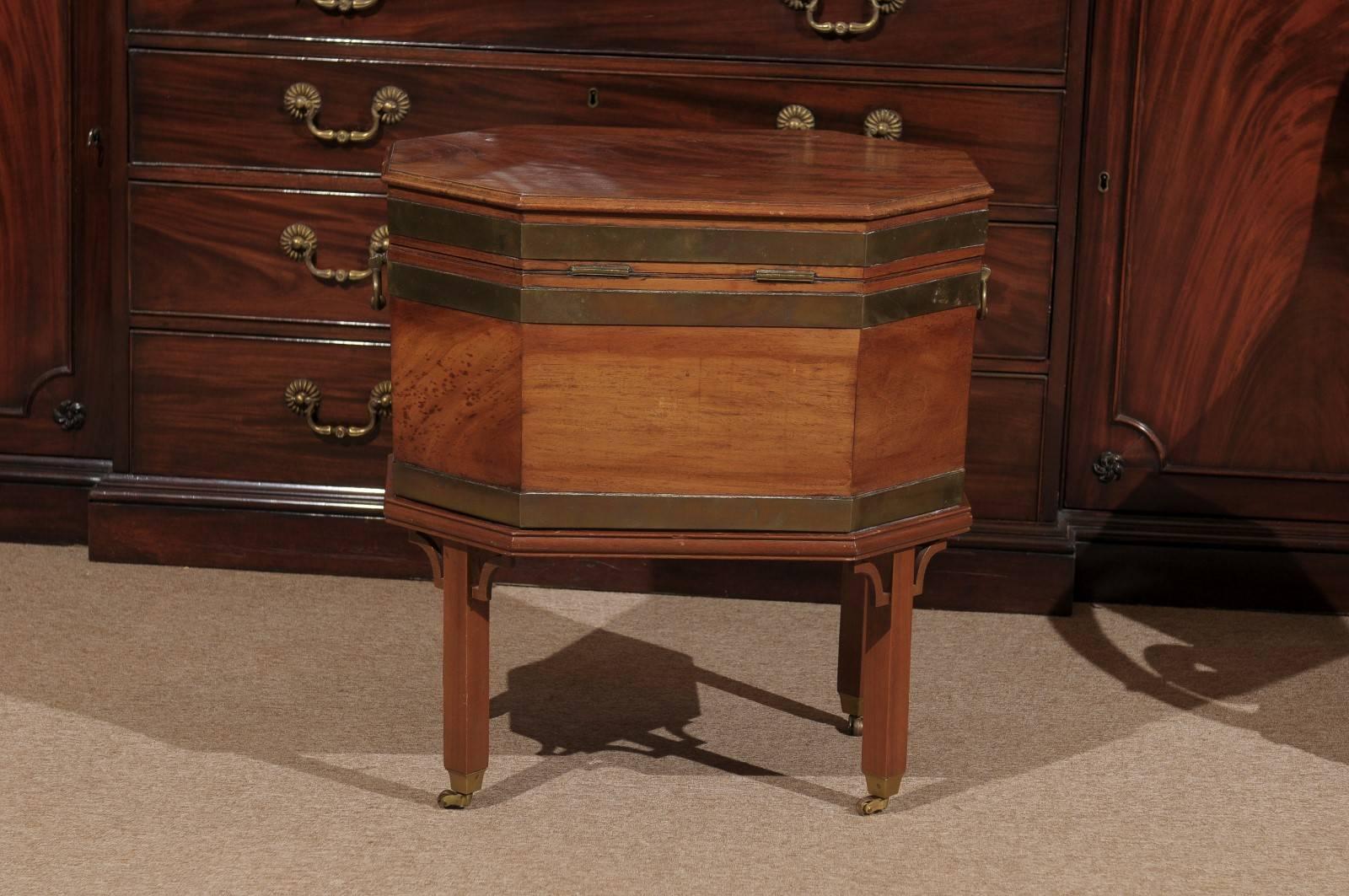 Octagonal shaped Cellarette in mahogany with brass banding and handles mounted atop a later stand with bracket corner molding and castors, England, Early 19th century.