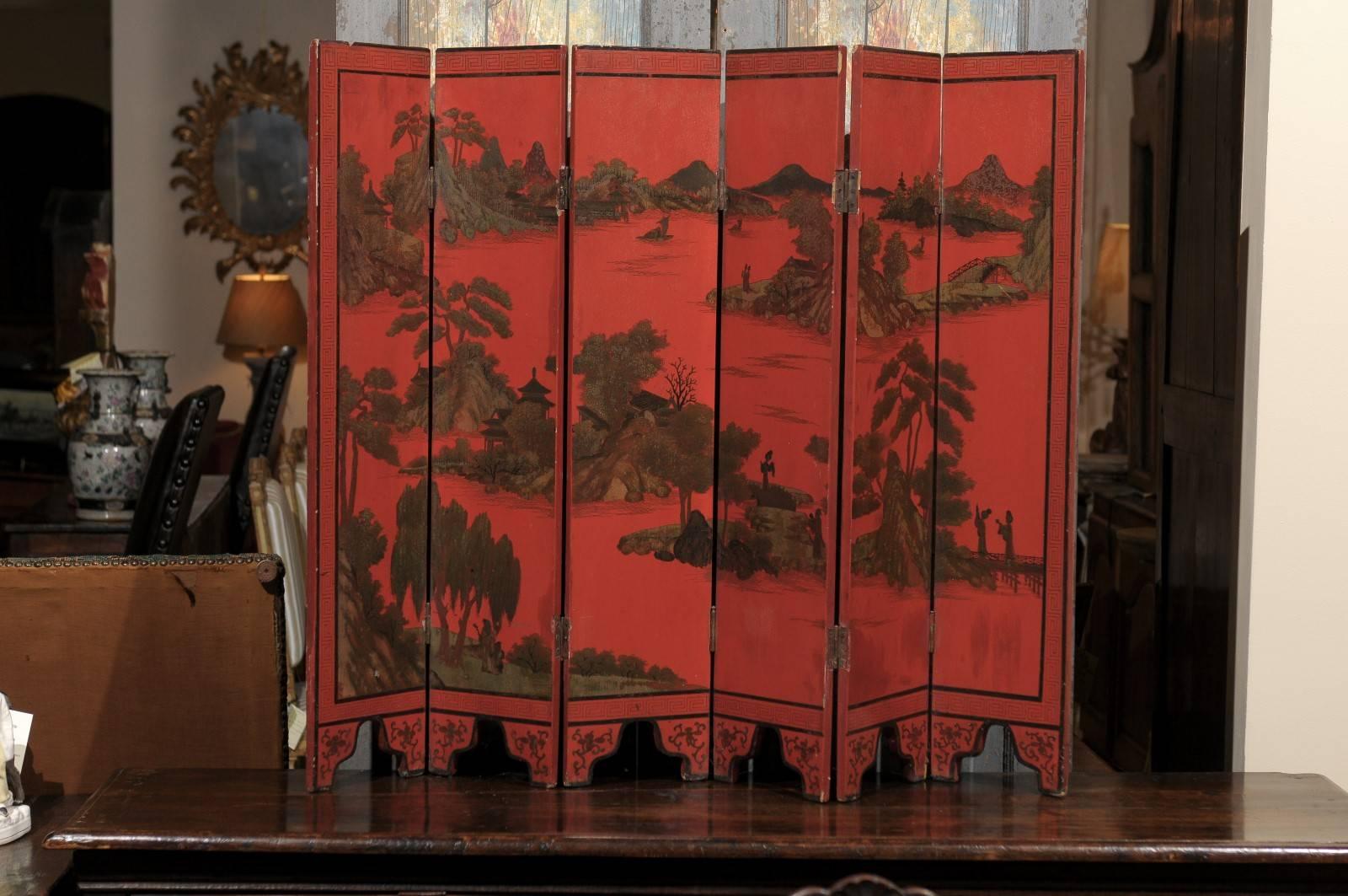 A 19th century Chinese red 6-panel lacquered screen with chinoiserie and Greek key design.