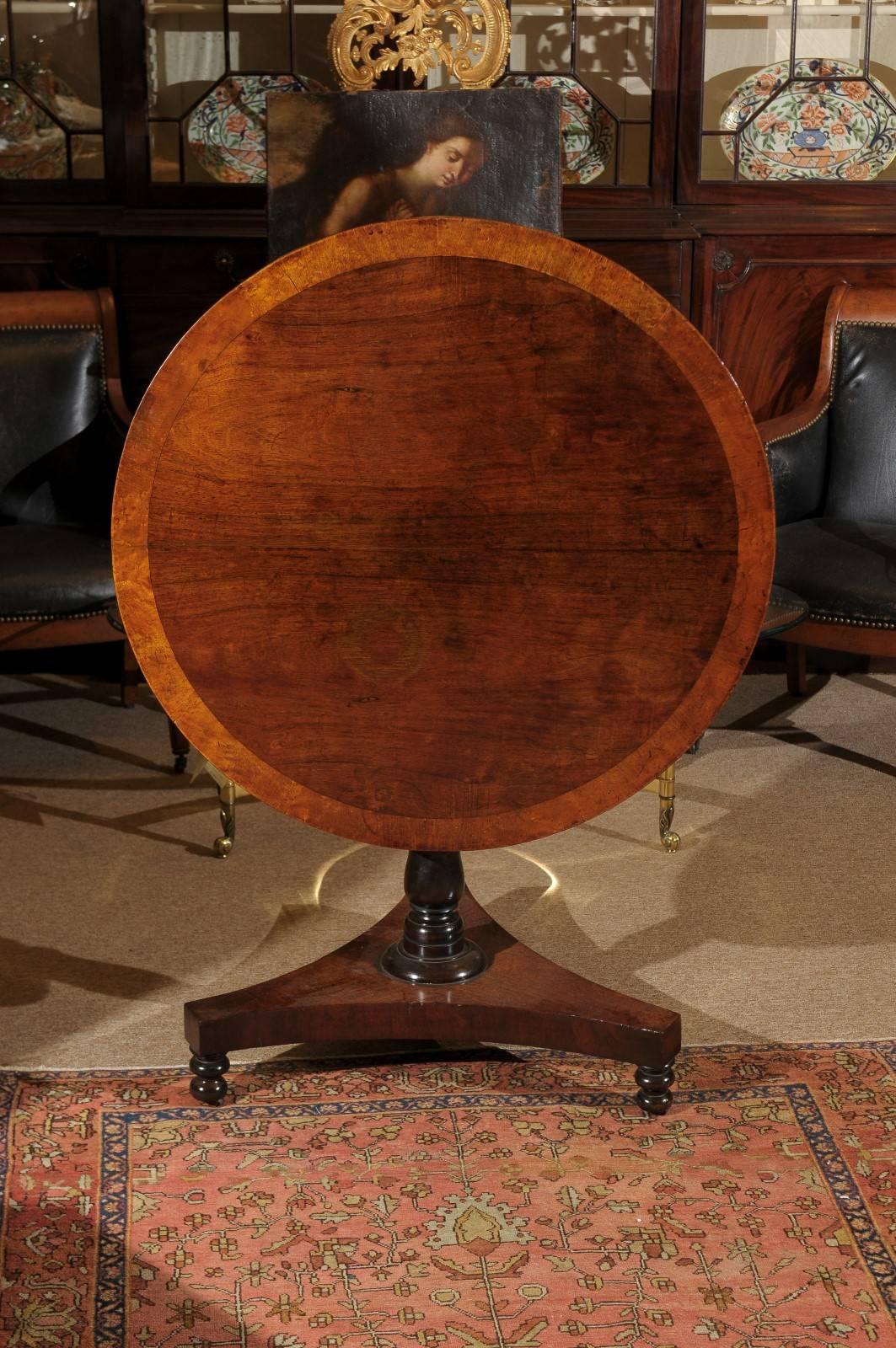 Mahogany tilt-top gueridon with a carved pedestal base in mahogany with crossbanding inlay, England, 19th century.
