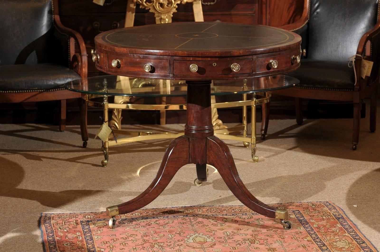 Drum table in mahogany with embossed black leather top atop pedestal base with tripod splay legs, England 19th century.