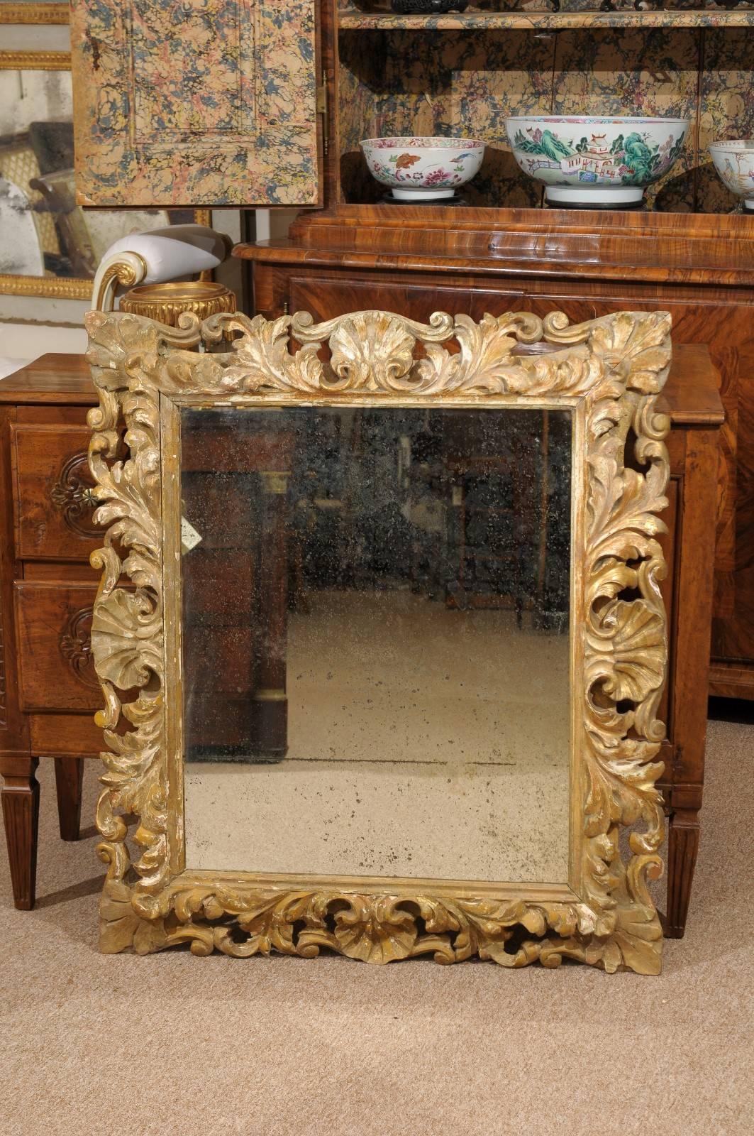 19th century gilt-wood Italian mirror in the Rococo style. The aged mirror with acanthus leaf, shell and pierced carved frame.

  
