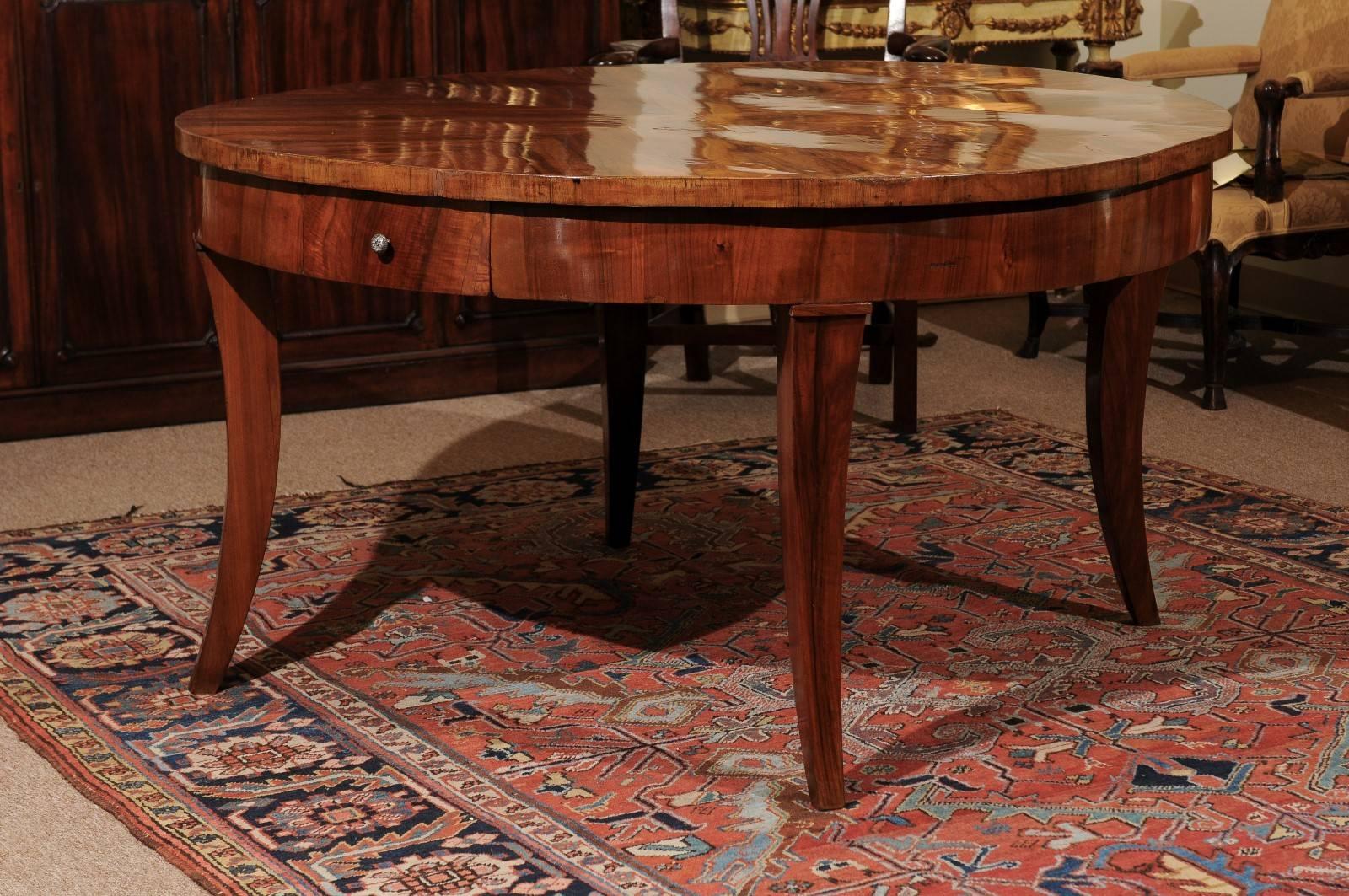 Large 19th century Italian walnut round dining or center table with small drawer in frieze and four graceful down-swept legs.