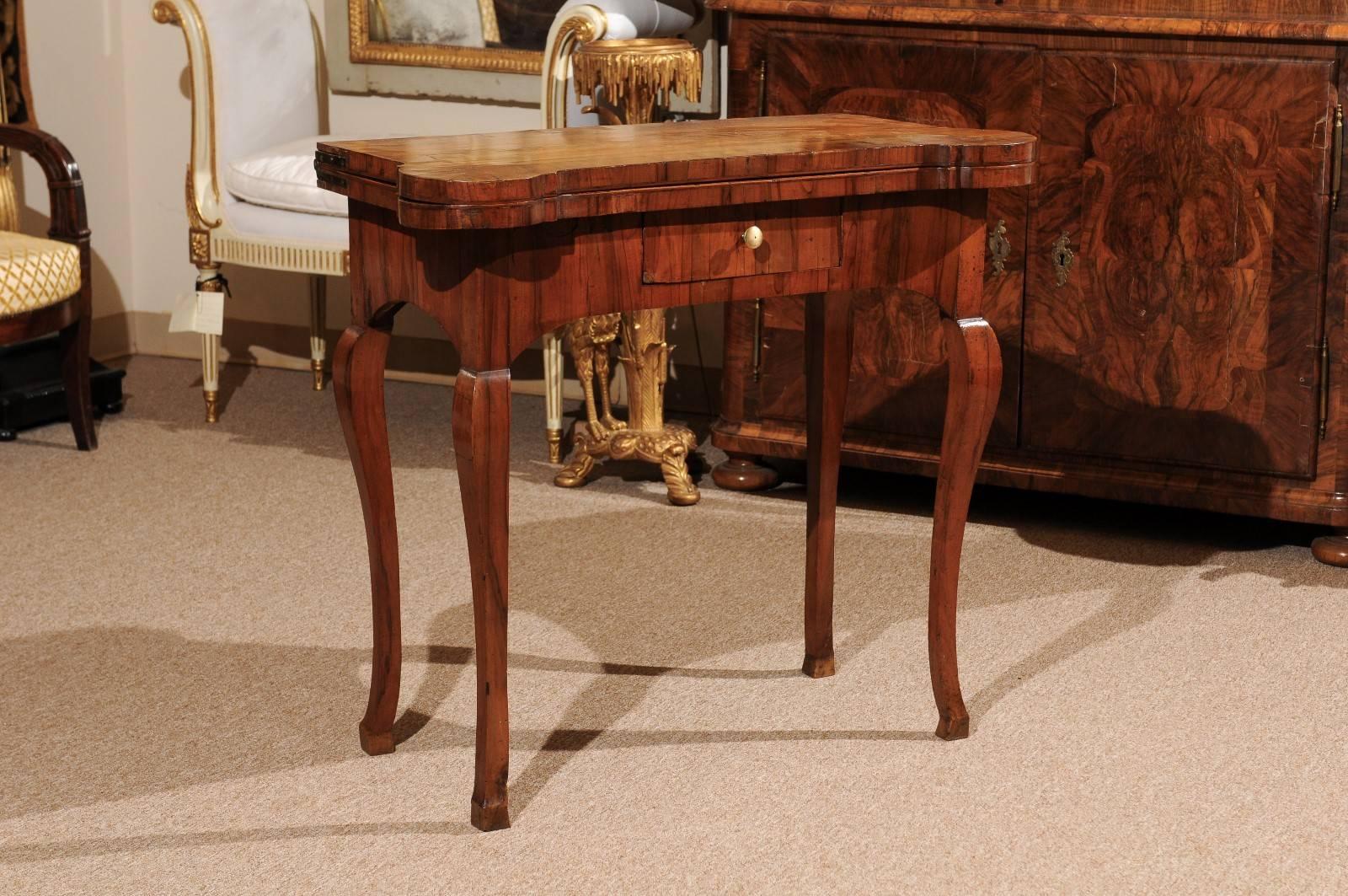 18th century Italian flip-top game table in olivewood with cabriole legs terminating in hoof feet and one (1) drawer. The table opens with a drawer action mechanism to reveal square olivewood tabletop with crossbanding.