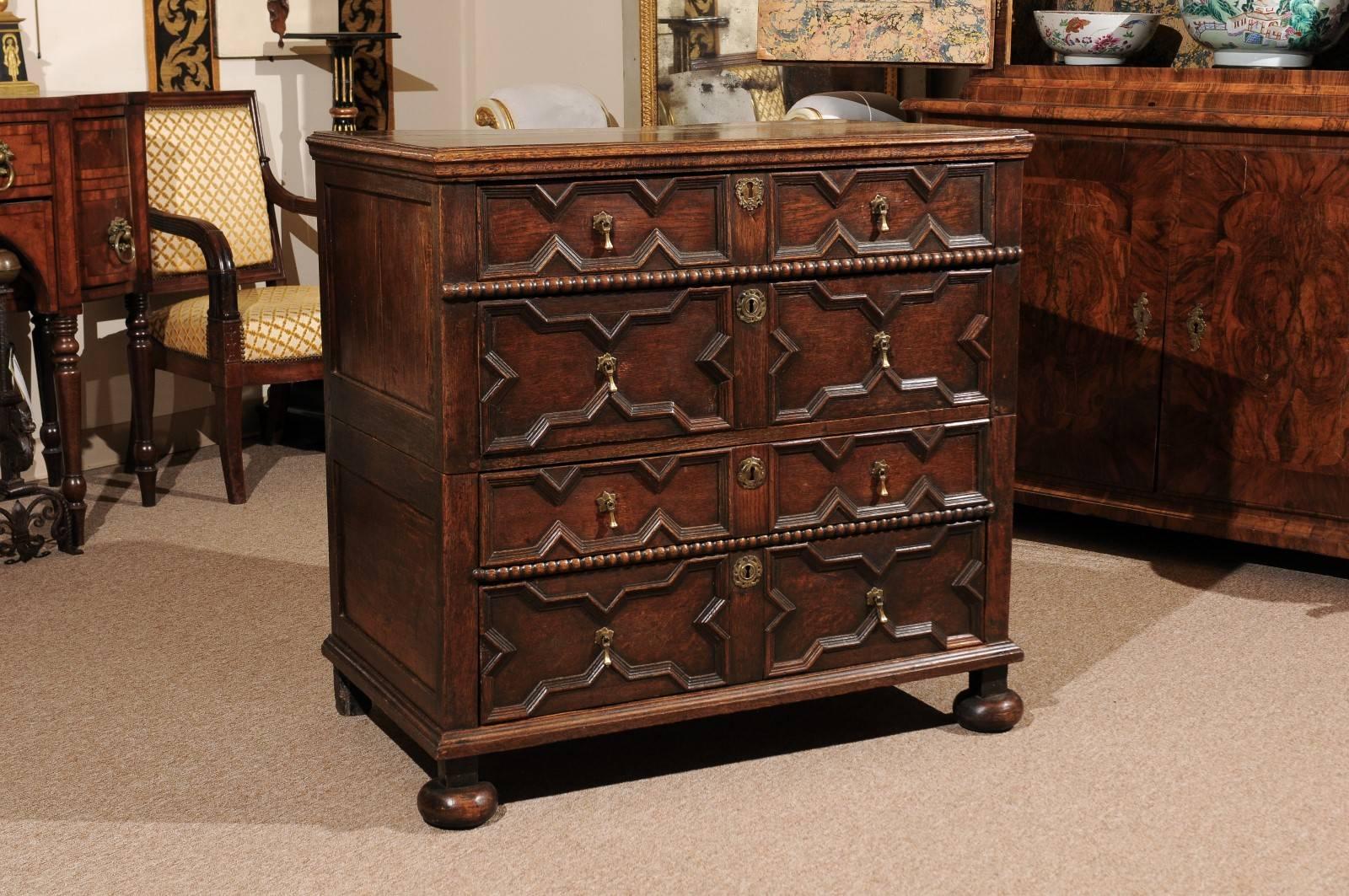 Jacobean style four-drawer chest in oak with bun feet, England 18th century.