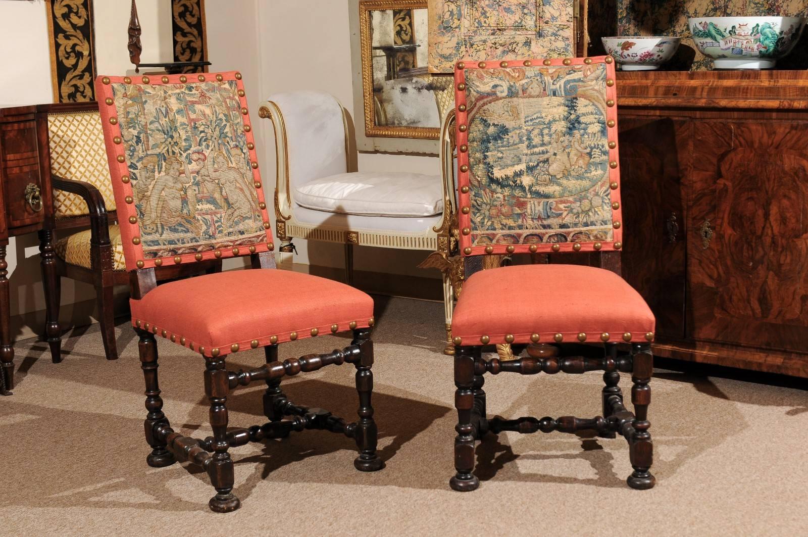 Pair of early 18th century oak side chairs in the Louis XIII style with period tapestry upholstered backs, brass nailheads and linen seats in salmon hue. The legs and stretcher with turned detail. All resting on bun feet. 

  