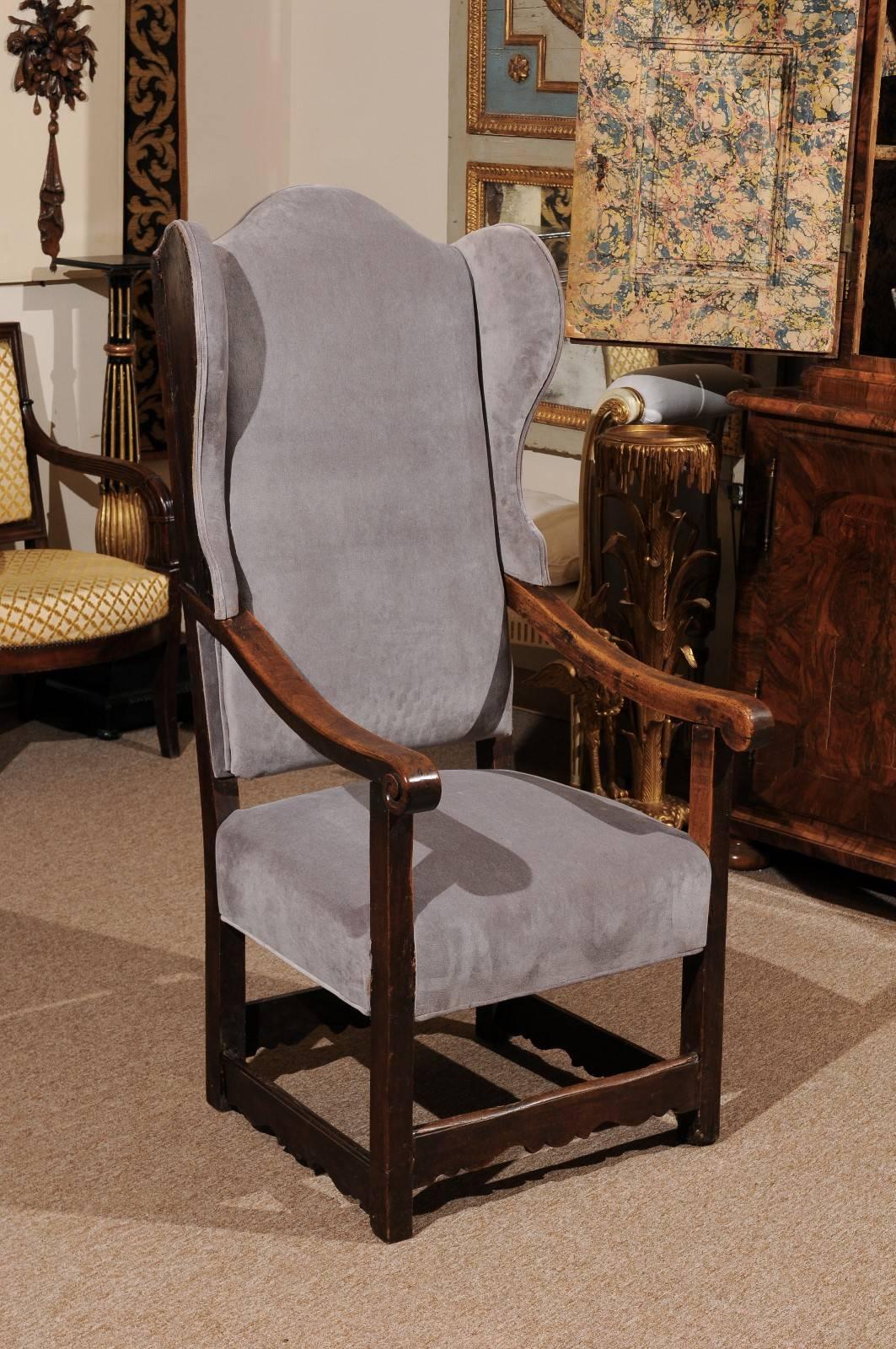 Wing chair in walnut with carved stretchers and new grey velvet upholstery, Italy, 18th century.