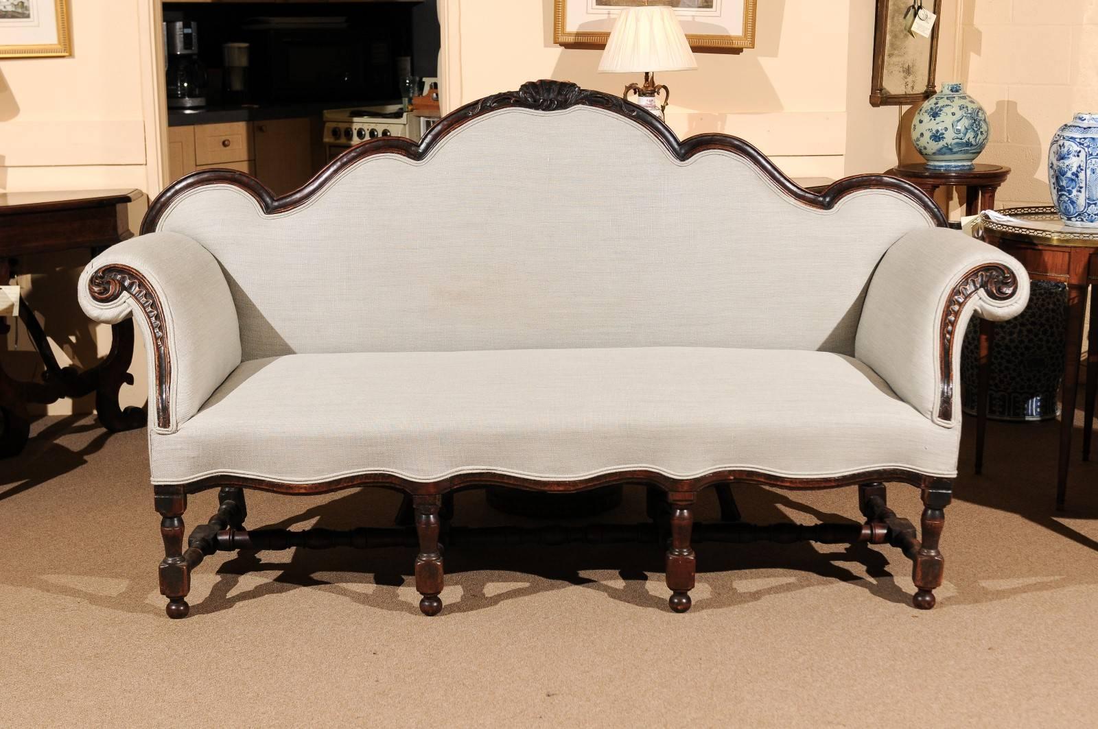 Transitional Louis XVIII or Rococo sofa in walnut with turned legs and stretcher, carved shaped back and scroll arms, Italy 18th century. Dark walnut finish and grey linen upholstery.