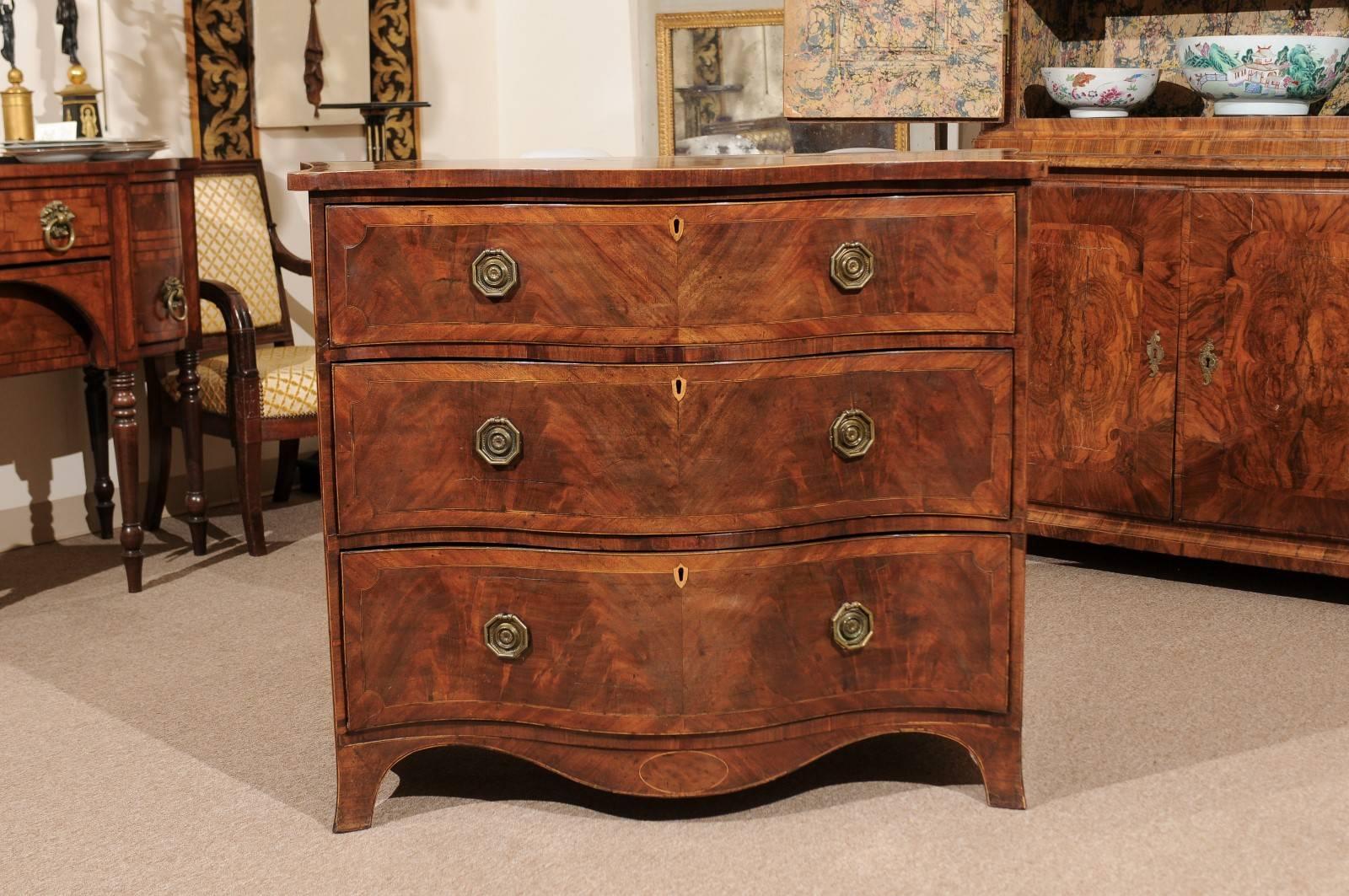 English Hepplewhite style mahogany serpentine chest with three drawers, string inlay, cross-banding, splayed legs and shaped apron.

 