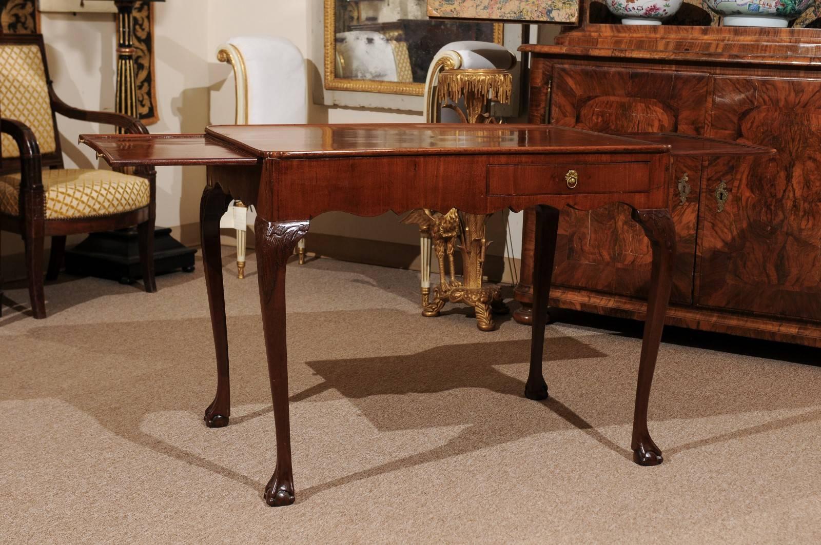 A George III mahogany tea table featuring 2 slides, drawers, cabriole leg ending in ball and claw feet.