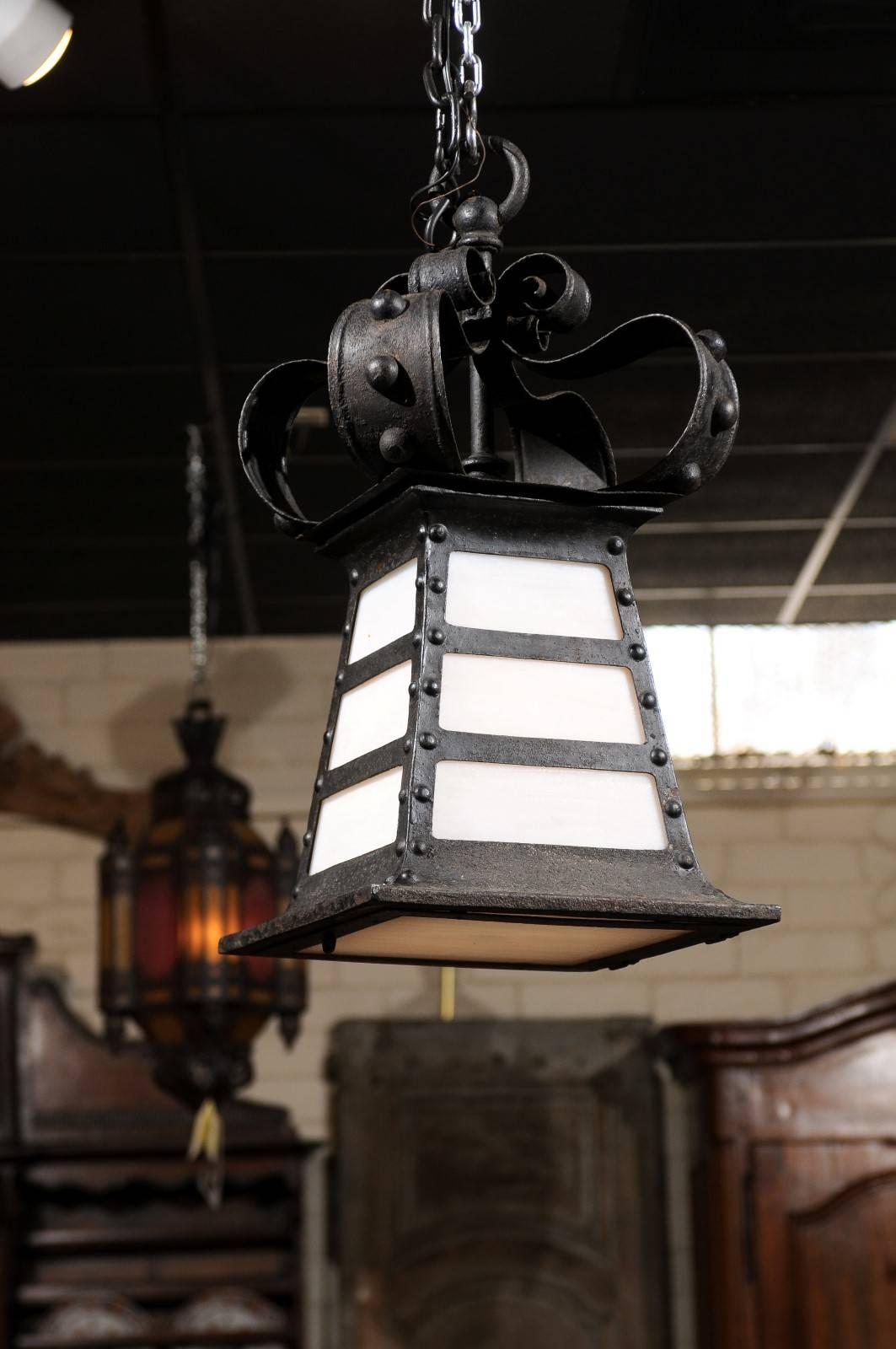 A French early 20th century iron lantern with crown detail and 4 sides each with 3 graduating white rectangular glass panes.