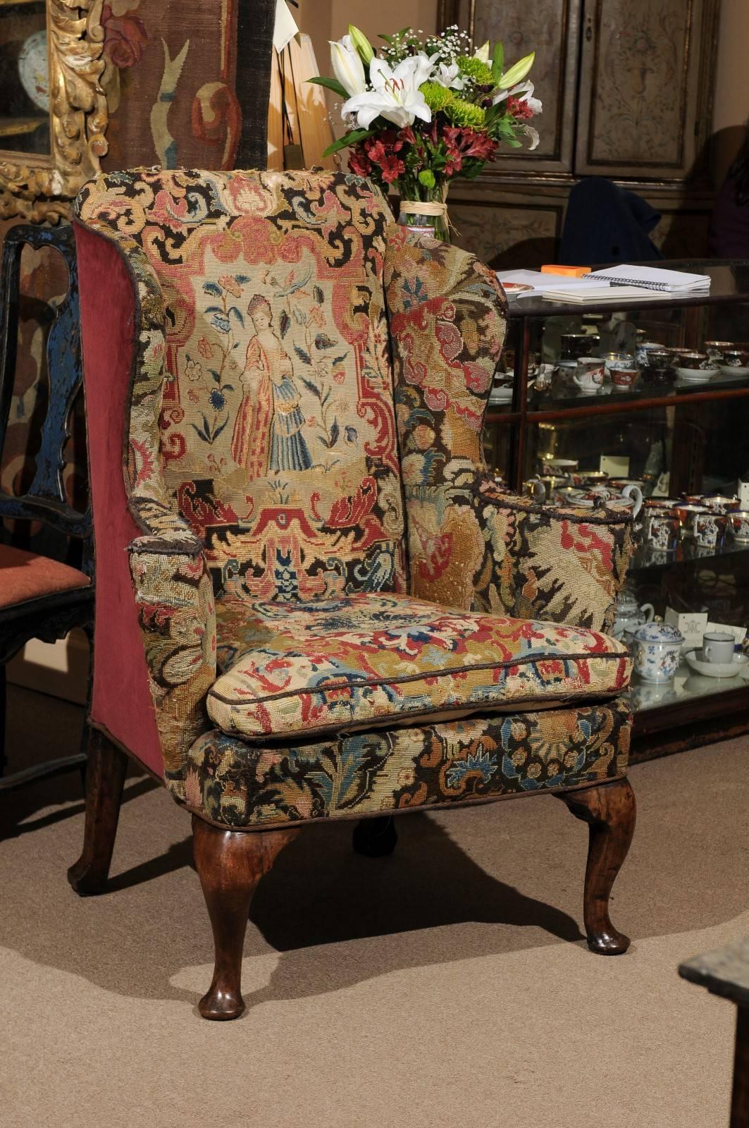 Walnut Queen Anne Wing chair upholstered in needlepoint tapestry featuring a woman in fancy dress with flowers and a bird. Back and sides upholstered in burgundy velvet.