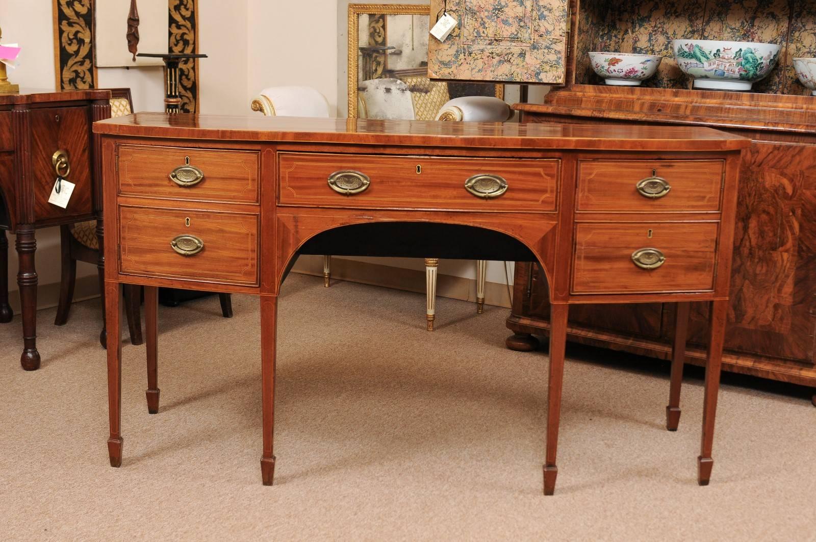 An early 19th century English George III mahogany bow-front sideboard with rosewood crossbanding, boxwood string inlay, 2 cabinets flanking center drawer ending with tapered legs and spade feet.