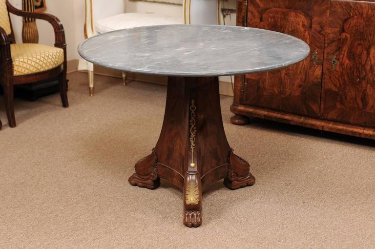 Early 19th century Empire mahogany center table with grey dish marble top, ormolu mounts and paw feet.