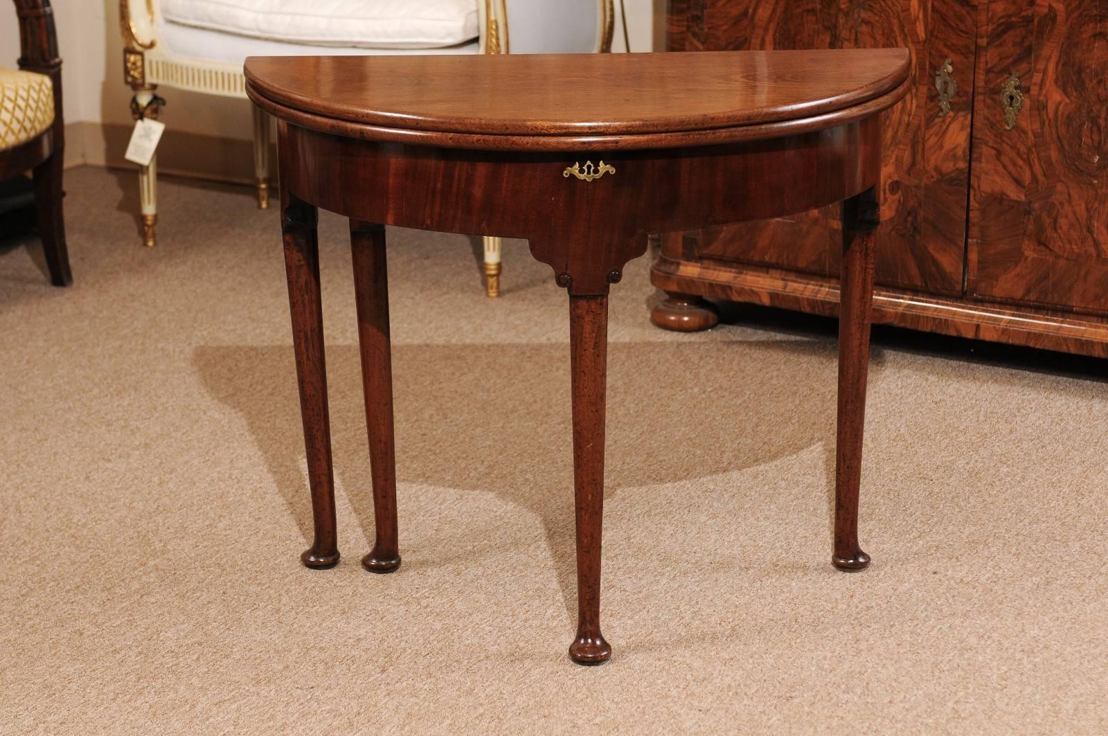 18th century English flip-top demilune-shaped console table in mahogany on pad feet, opens to circular game table with wood top.