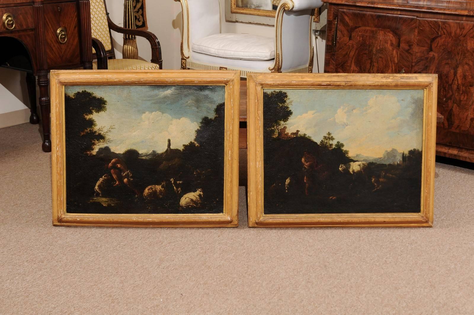 Pair of wood framed oil on canvas landscape paintings featuring goats in the foreground and village in the background, Italy 18th century. Frames in stripped wood finish.