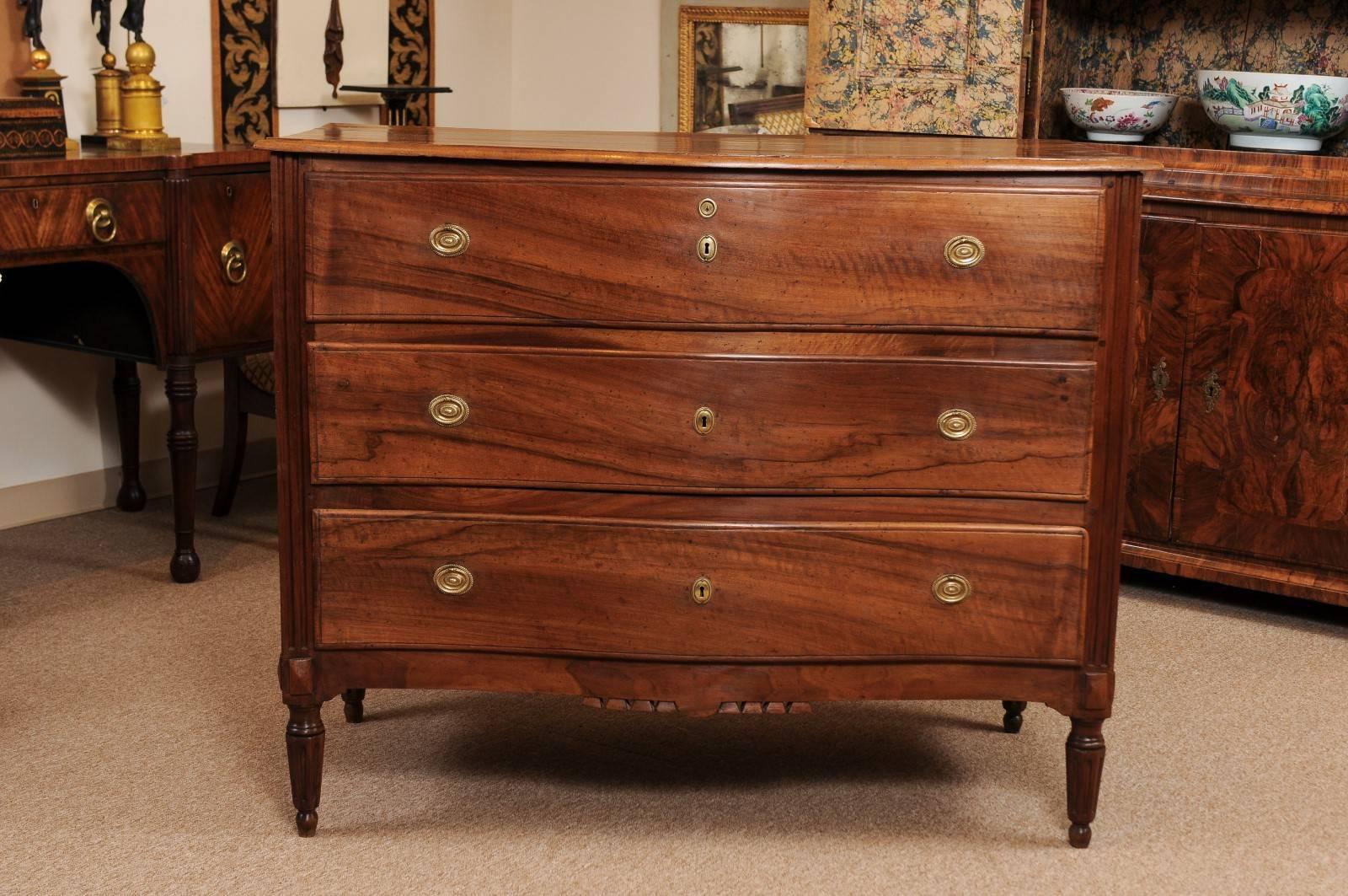 Late 18th century neoclassical walnut commode with serpentine front, three drawers, brass hardware, carved apron fluted legs.

William Word Fine Antiques, Atlanta's source for antique interiors since 1956.