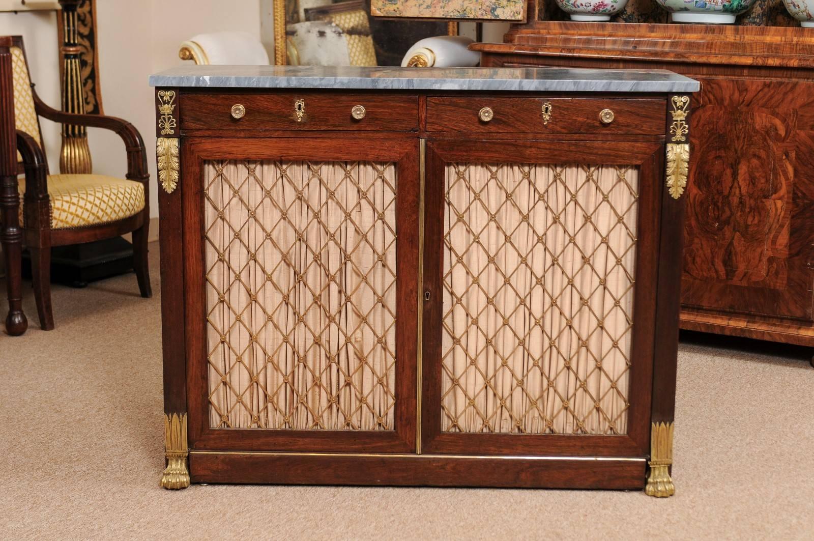 Early 19th century Regency rosewood cabinet with grey marble top, brass mounts and brass grill doors lined with fabric. The cabinet resting on paw feet.

  