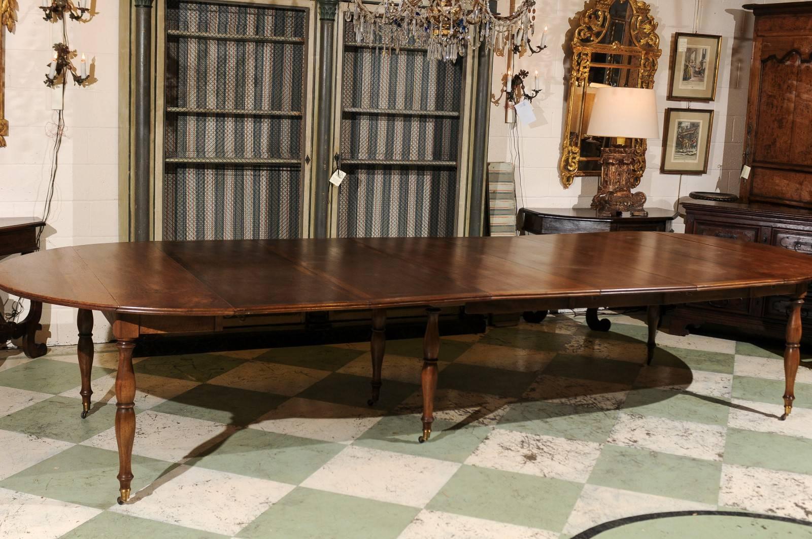 Large French extension dining table in walnut with turned legs all resting on brass castors. Table has six leaves (each 19.5