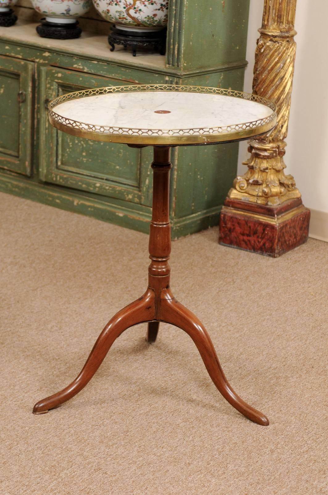 The Louis XVI walnut gueridon /round side table with revolving white marble top with brass gallery and supported by tripod pedestal base. 

      