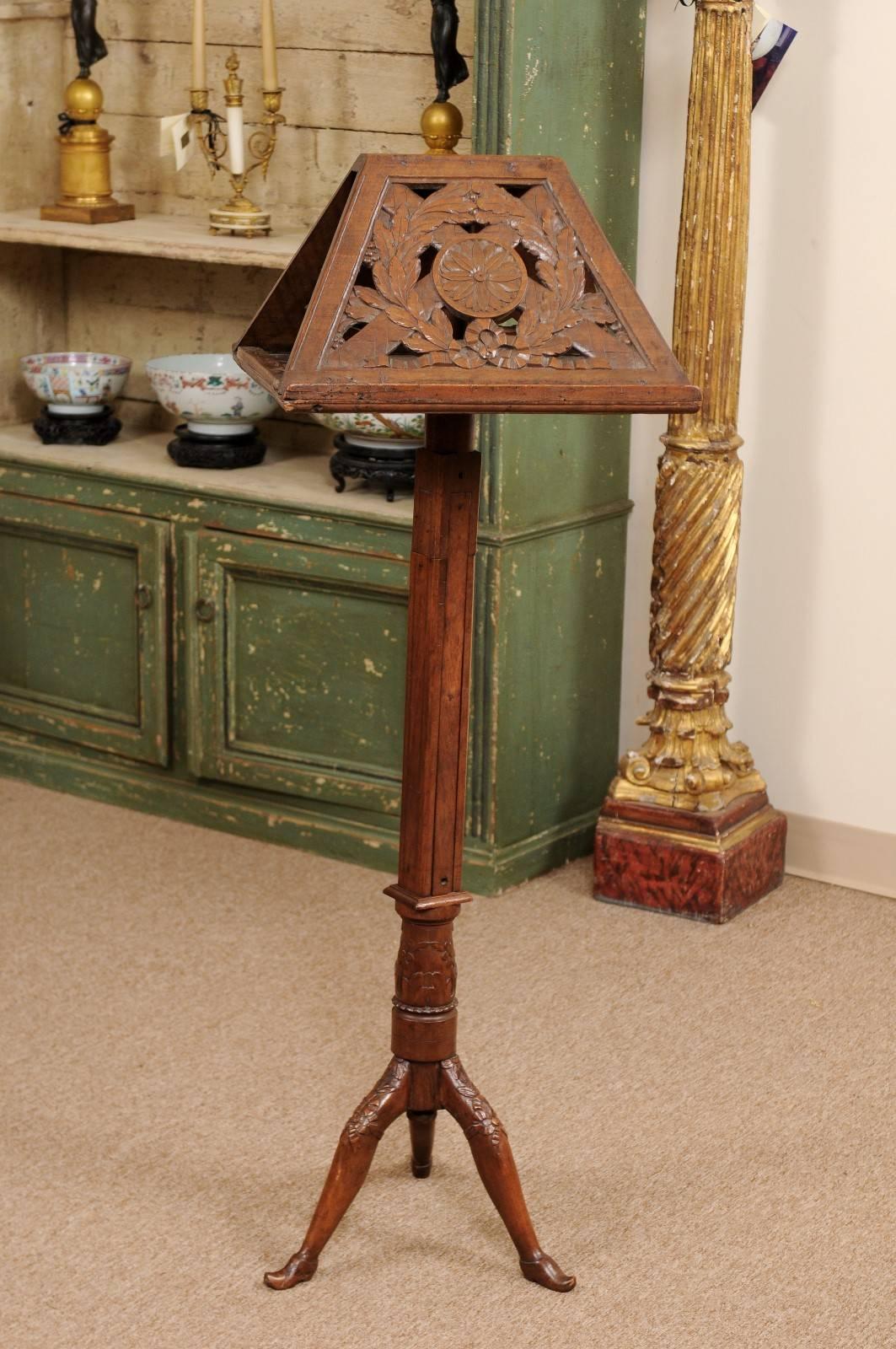 Louis XVI period music stand in walnut with rotating duet stand featuring carved laurel wreath and rosette paterra, tripod base terminating in buckled shoe feet.