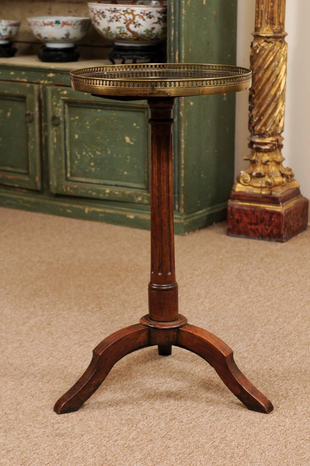 The 19th century French Louis XVI style gueridon in mahogany with grey marble top and brass gallery above turned fluted pedestal terminating in tripod base.
 