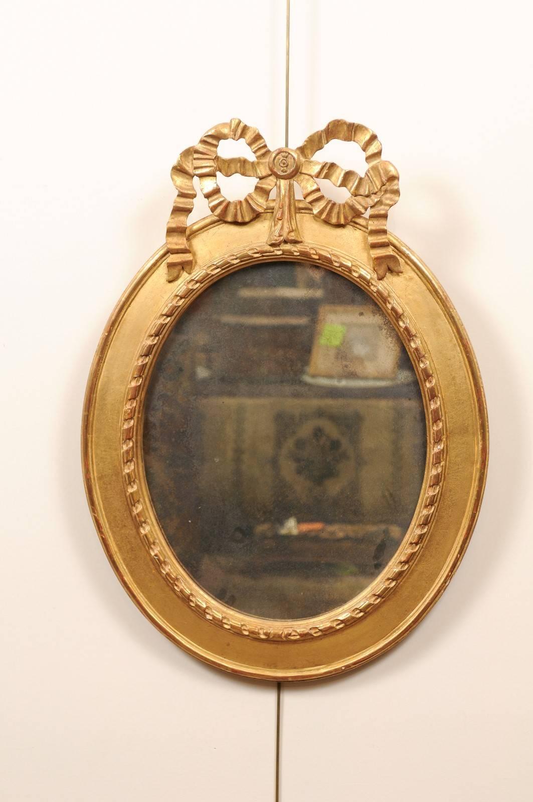 Paire de miroirs ovales à arc en bois doré, 20e siècle. Les deux plaques de miroirs avec traitement de vieillissement.
