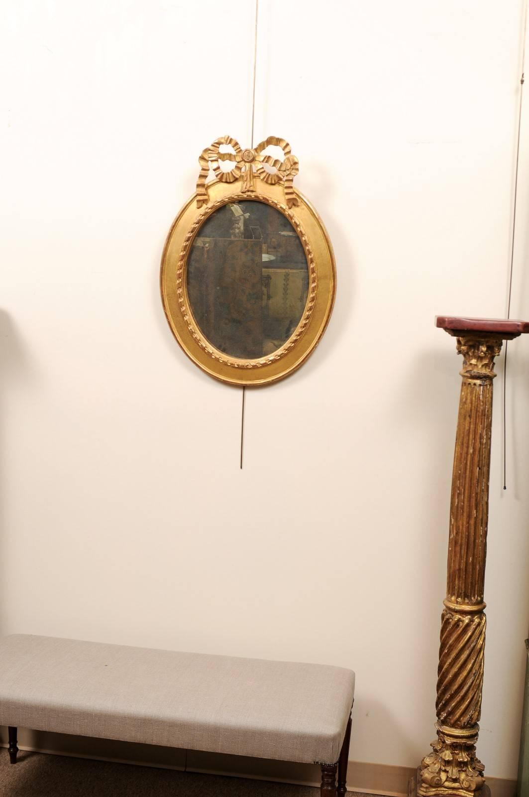 Louis XVI Paire de miroirs ovales en bois doré surmontés d'un nœud, 20ème siècle en vente