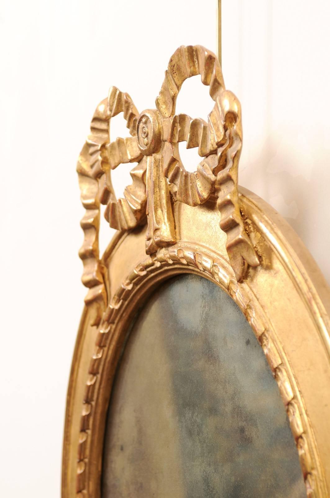 Paar ovale Spiegel aus vergoldetem Holz mit Schleifenaufsatz, 20. Jahrhundert im Angebot 1