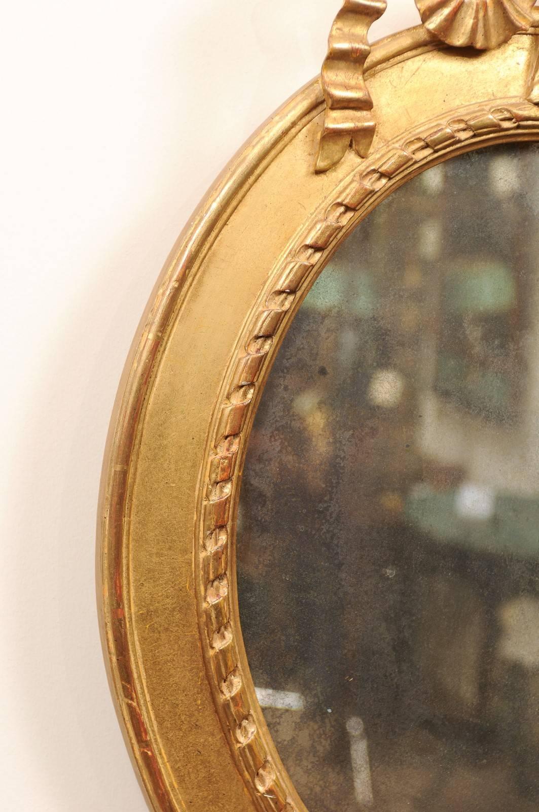 Paire de miroirs ovales en bois doré surmontés d'un nœud, 20ème siècle en vente 2