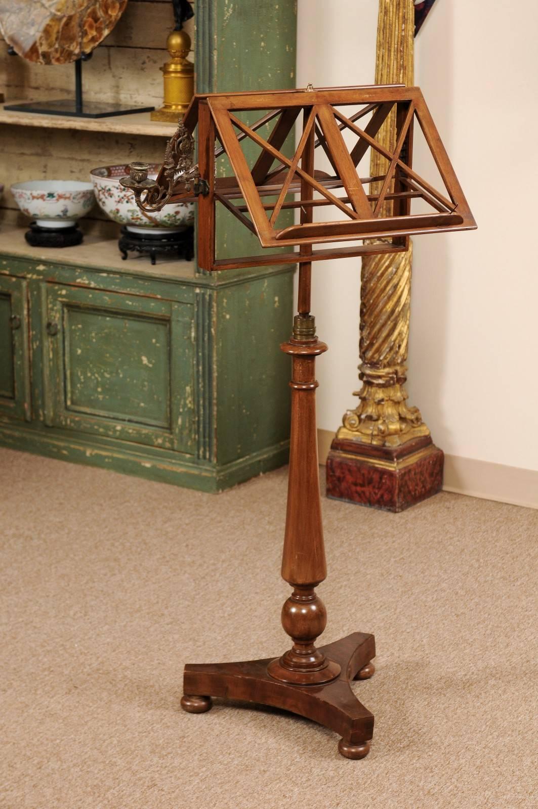 19th century French mahogany music stand with candle sconce, turned pedestal base, and bun feet. Dual sided for use in duets.
