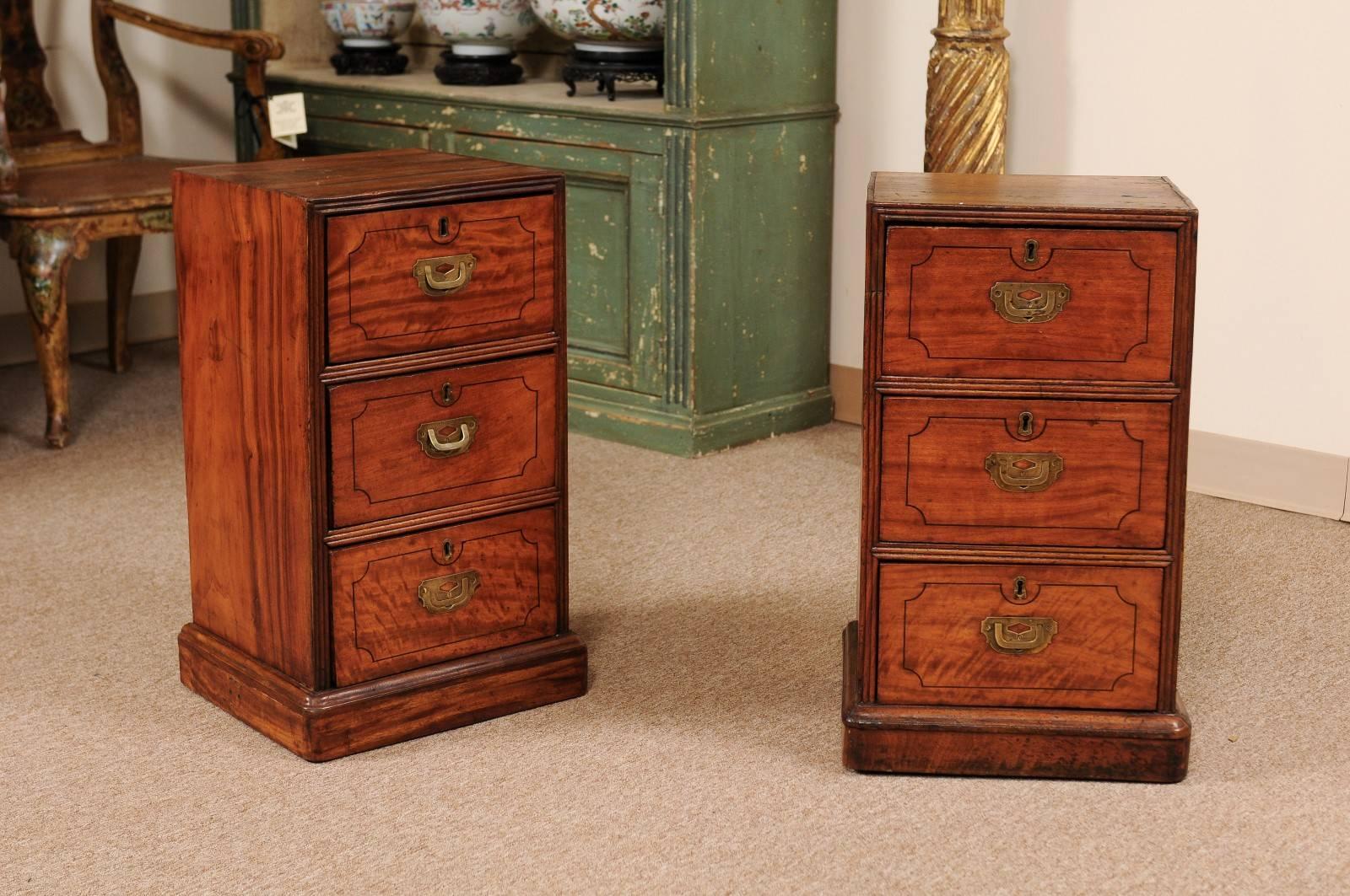 Pair of 19th century English mahogany bedside tables with three drawers in the Campaign style. Tables were the pedestals to a Partner's desk later converted into bedside tables.