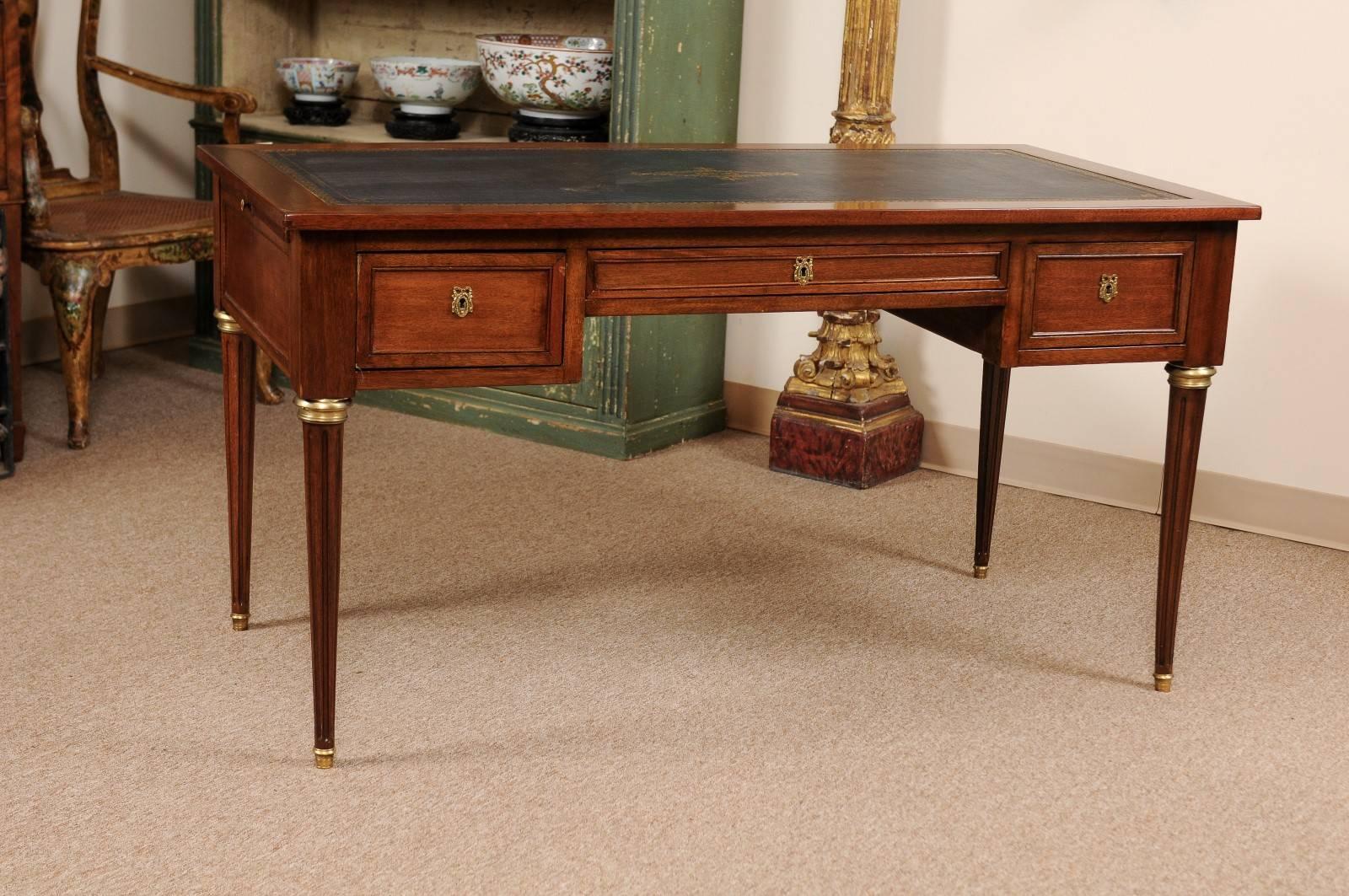 French Mahogany bureau plat/writing desk with dark blue leather embossed leather top, slides, fluted carved tapered legs. 

William Word fine antiques: Atlanta's source for antique interiors since 1956. 

