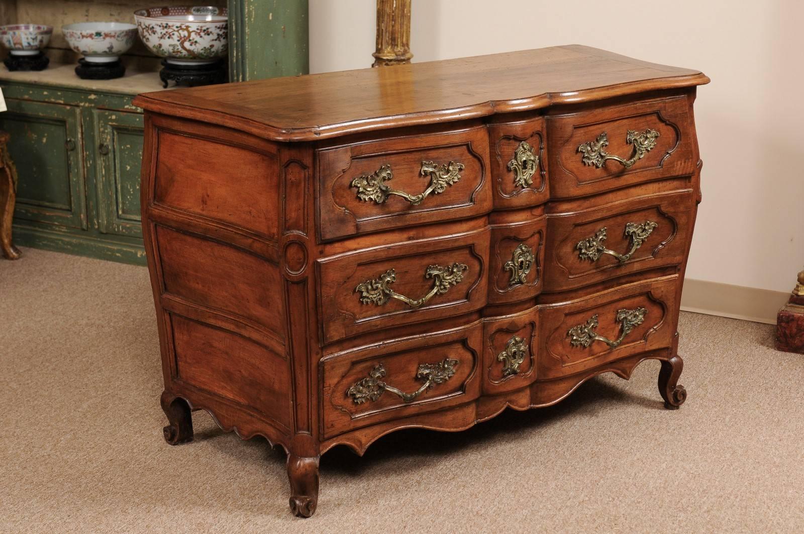 Louis XV period commode in walnut with three-drawers, linen fold front, and scroll feet, France 18th century.