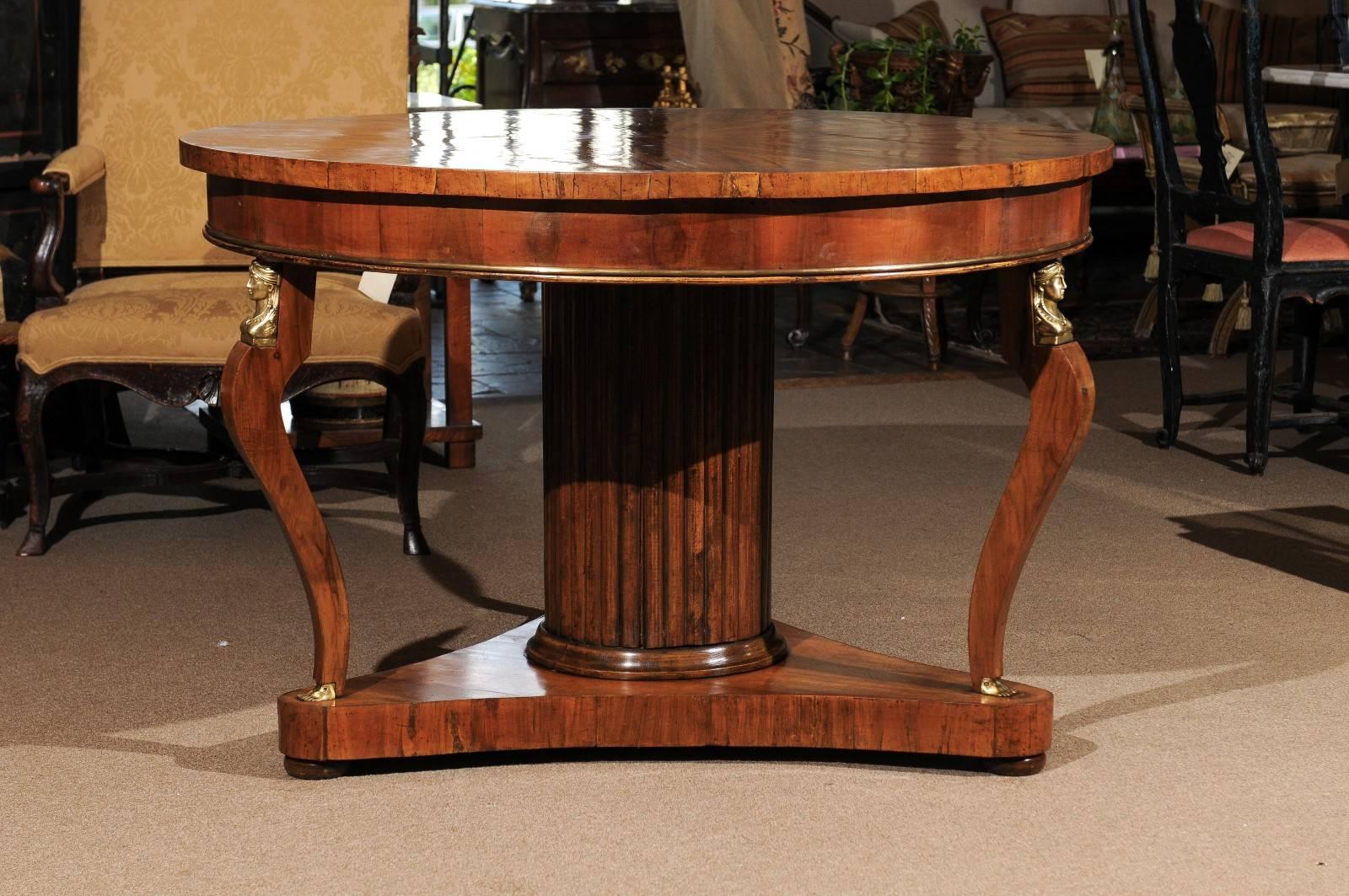 Early 19th century, Italian walnut center table with sunburst pattern veneer on top, brass caryatid mounts & inlay. The top resting on a column pedestal and 3 saber legs. 

William Word Fine antiques: Atlanta's source for antique interiors since