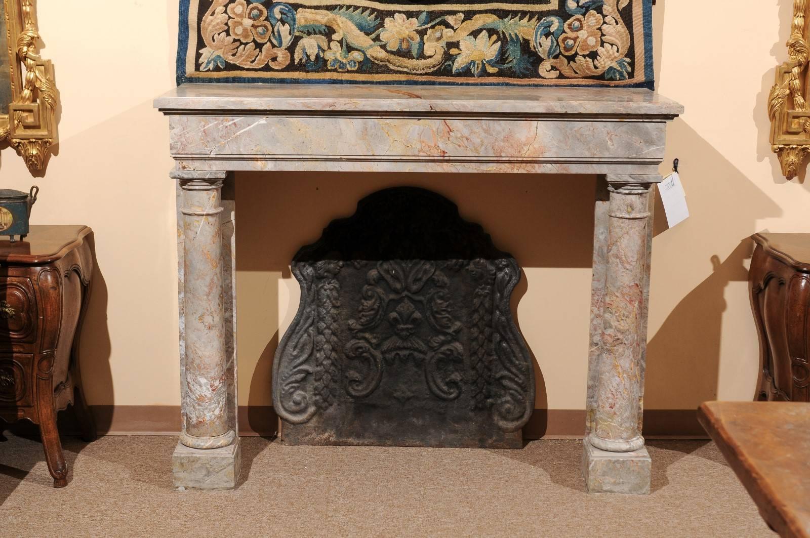 Large Neoclassical Style Marble Mantel featuring Column on each side. 19th Century France. Marble is a light gray color with coral colored veining throughout. Interior Measurements:  41
