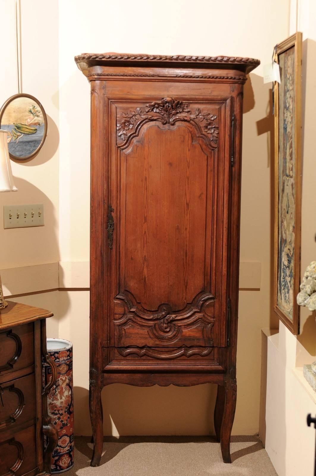 The petite French pine bonnetiere with removable cornice above cabinet with carved flowers on door. The interior with four shelves and drawer below. All resting on cabriole legs.