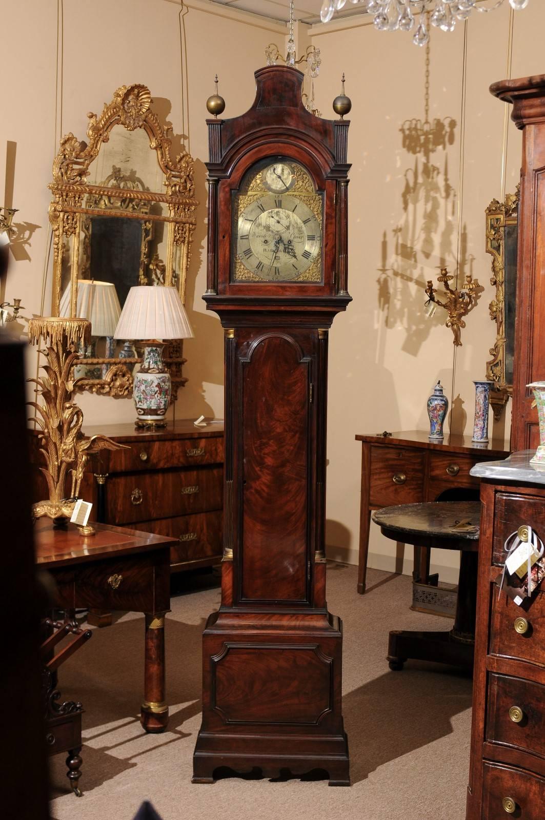 English mahogany tall case clock with bonnet top featuring two (2) finials and brass clock face signed by clockmaker 
