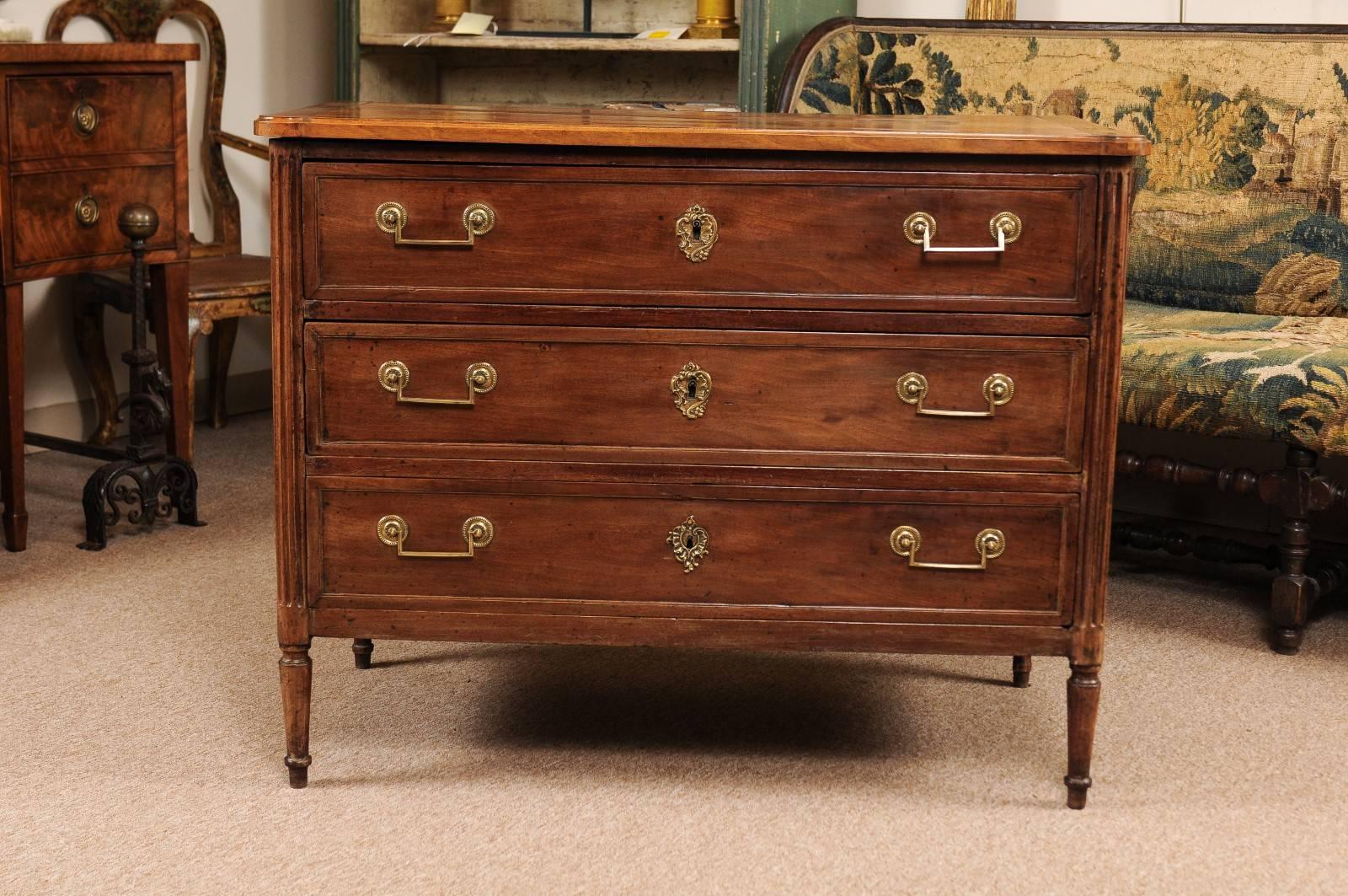 French Louis XVI walnut commode with three drawers, brass pulls, flanking rounded fluted columns and turned legs. 

William Word Fine Antiques: Atlanta's source for antique interiors since 1956. 

 