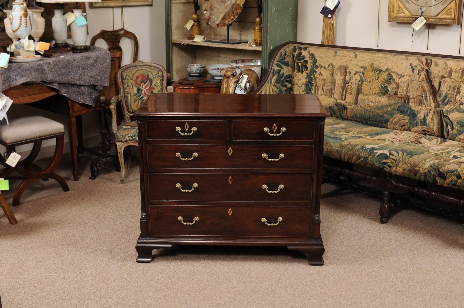 George III period chest in mahogany with five (5) drawers, reeded column detail, and ogee bracket feet, 18th century England.
