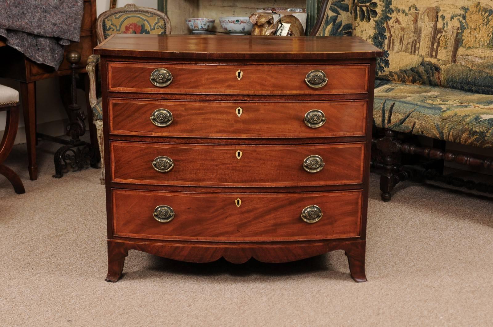 Sheraton mahogany and satinwood chest with bow front, four (4) drawers, and splayed feet, England, early 19th century.