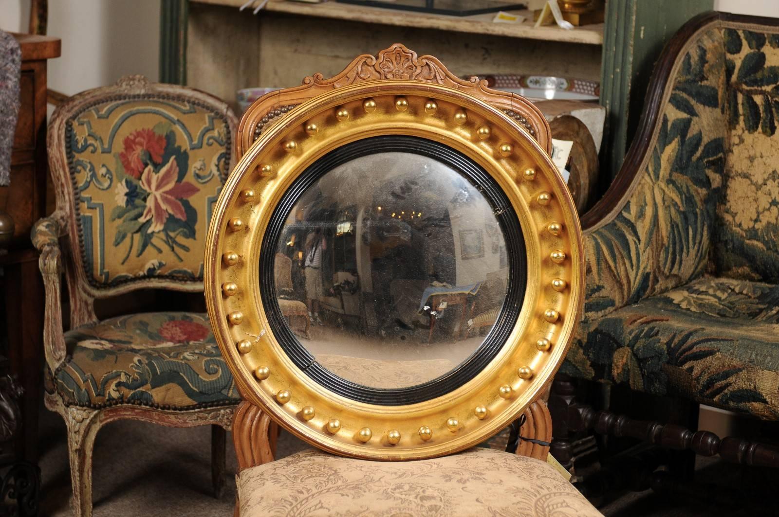 Giltwood bullseye mirror with convex mirror glass featuring gilt orbs around the outer perimeter and ebonized, ribbed detail, England, 19th century.