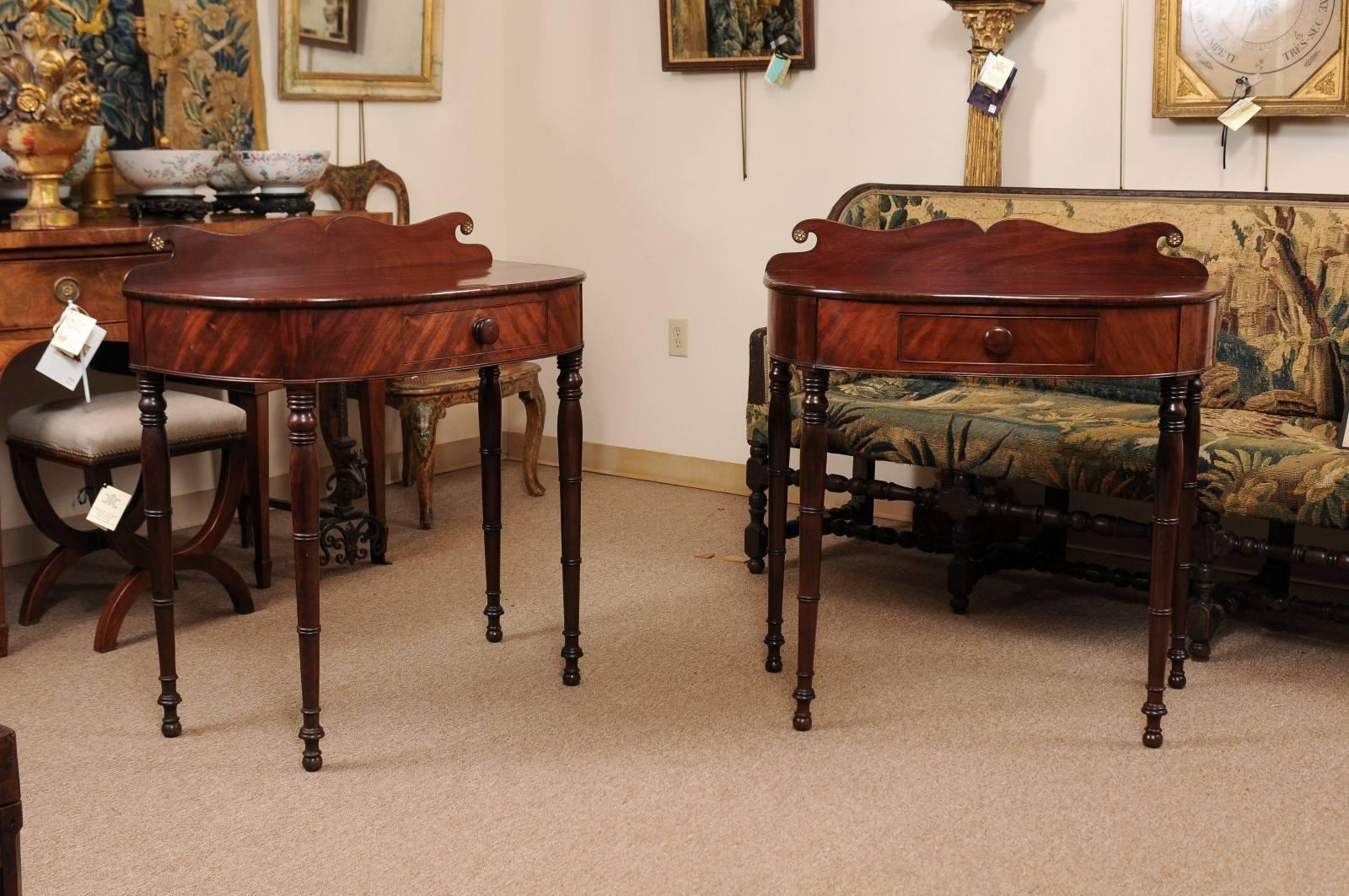Pair of Federal style, 19th century mahogany console tables with shaped back splash, drawer and turned legs.