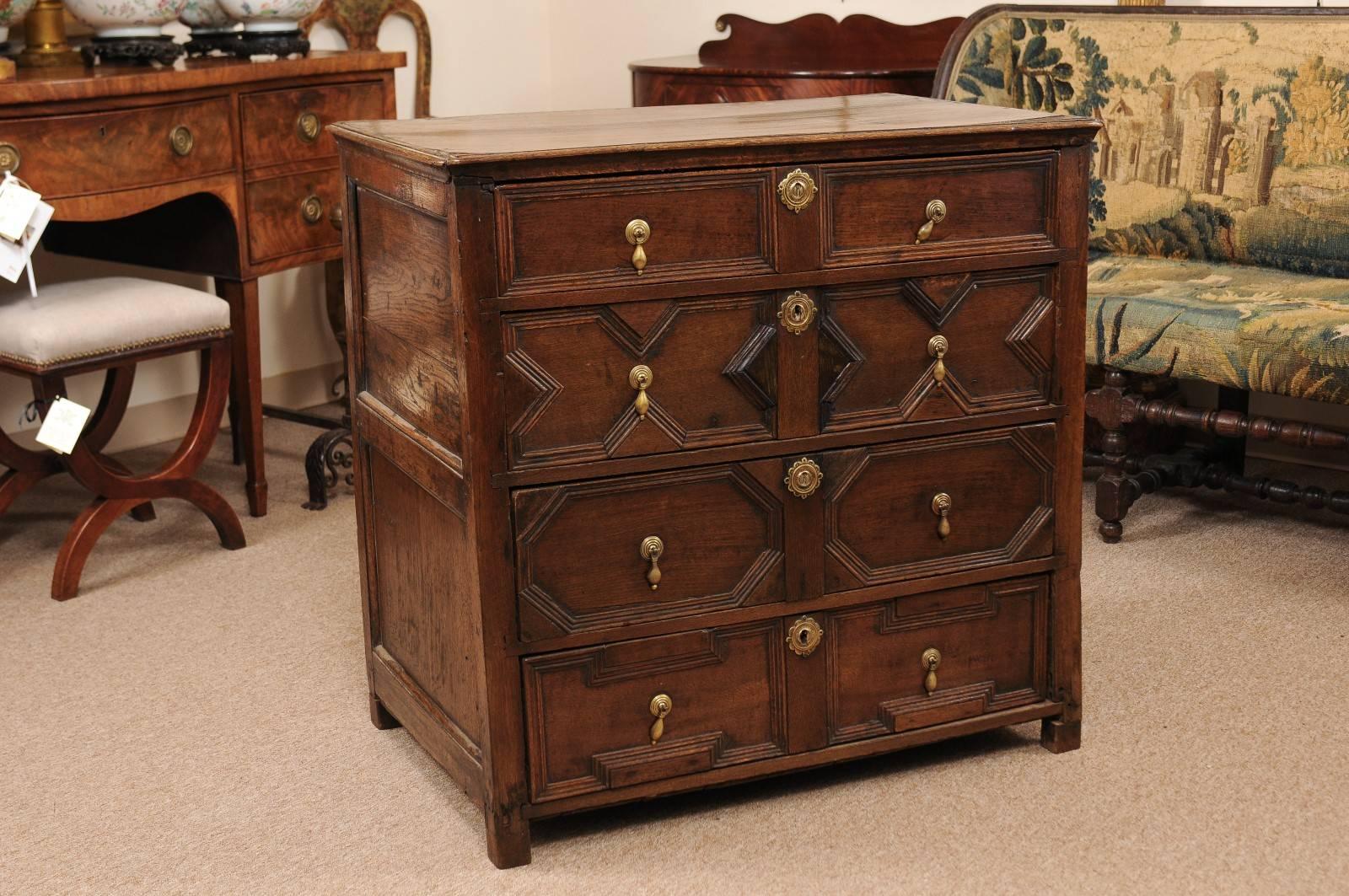 Jacobean style chest in oak with four intricately carved drawers and brass pulls, England, 18th century.