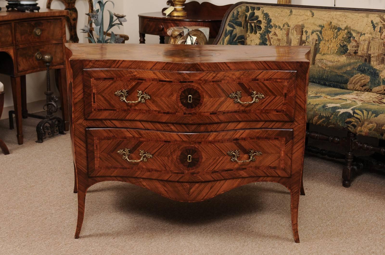 Italian inlaid commode in tulipwood and walnut with serpentine form, two drawers, shaped apron and splayed feet.

 